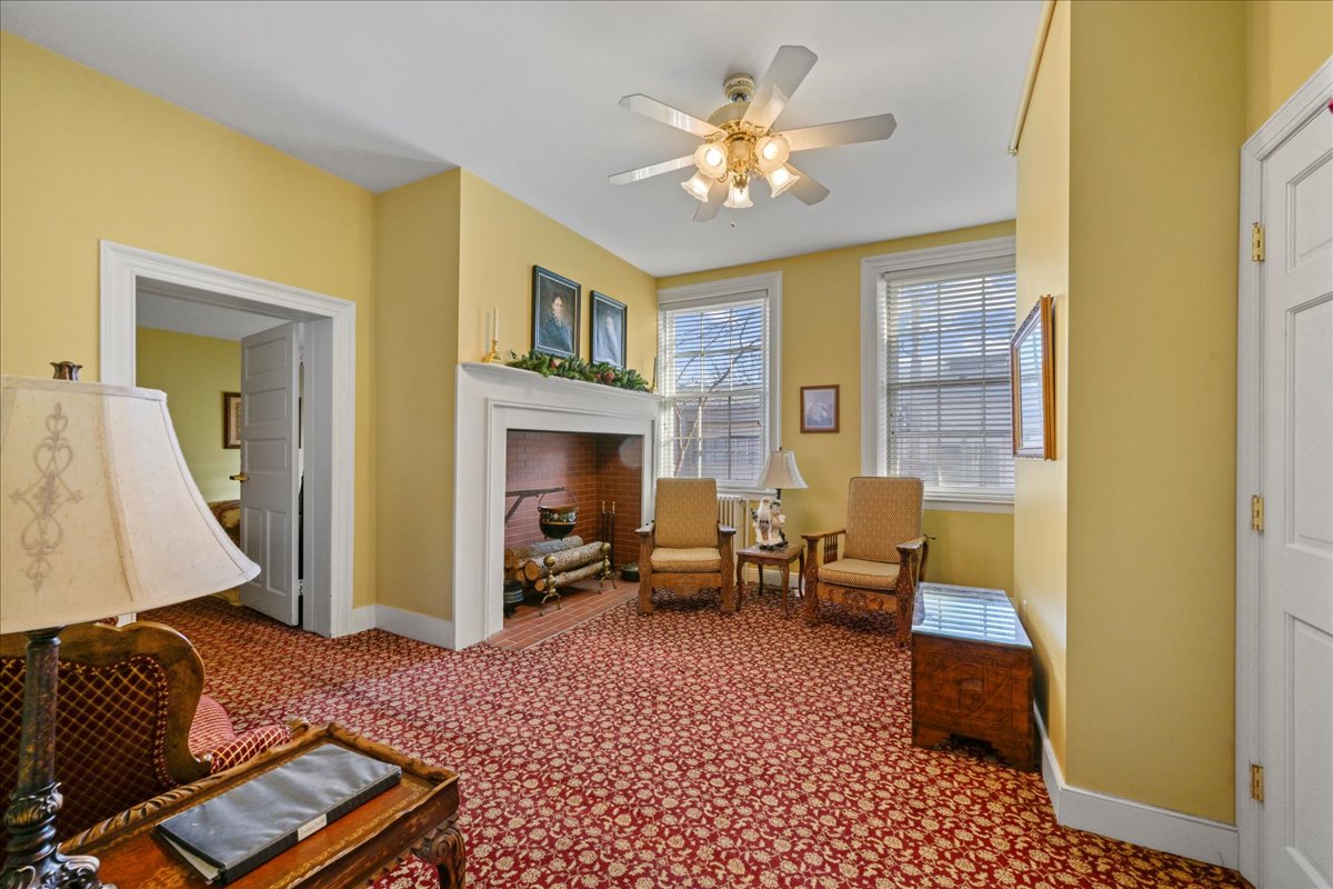 The Swope Suite features a carpeted bedroom, 2 queen-size beds with wooden headboards, 2 night stands with lamps, an electric fireplace, and a split HVAC unit.