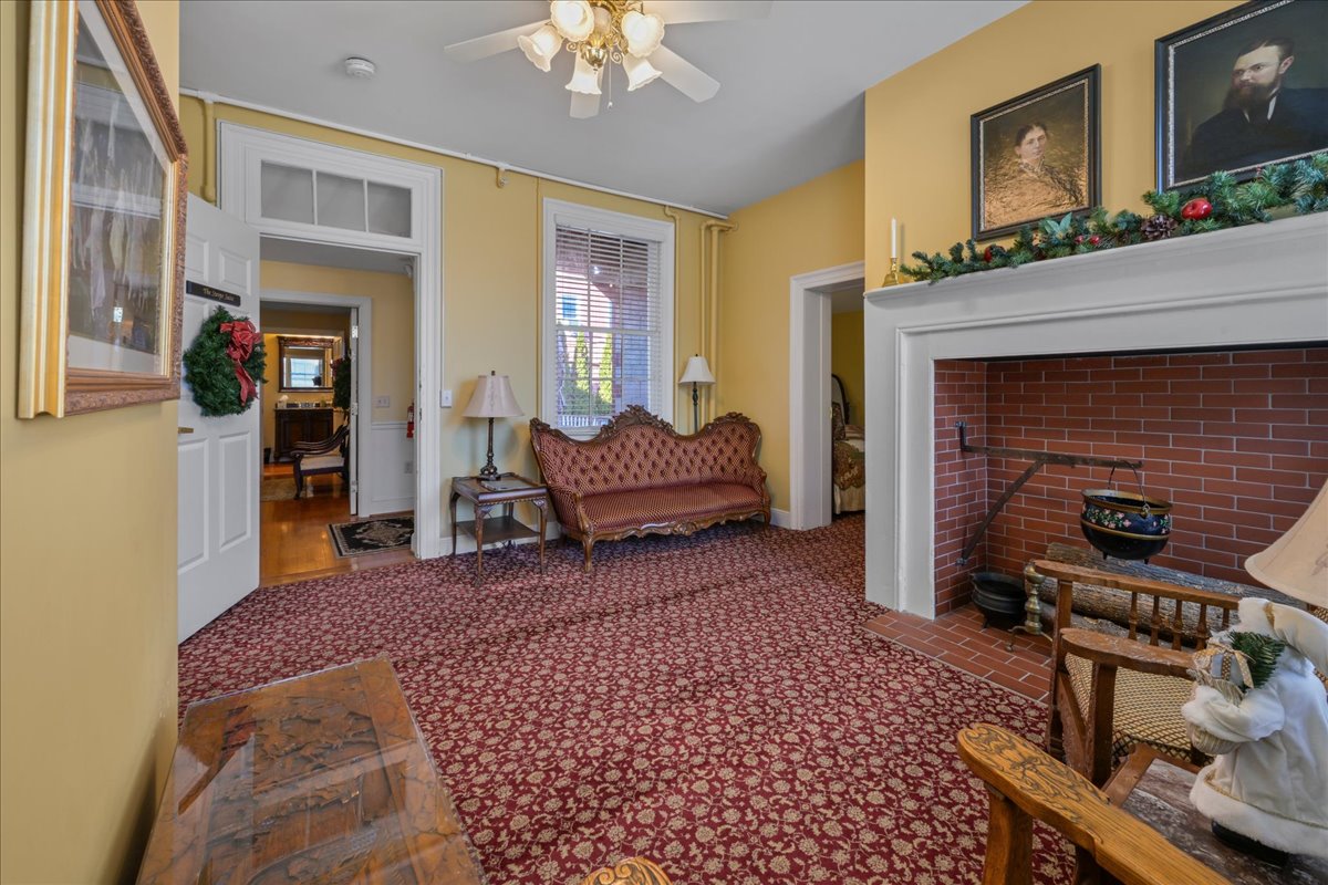 The Swope Suite with two queen-size beds, patterned bedspreads, and wooden nightstands flanking the beds. The walls are light yellow, and the carpet is a red patterned design.