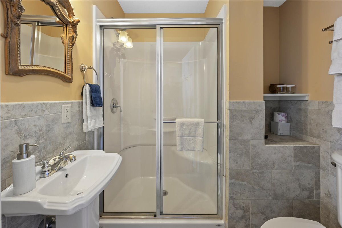 The Norther Spy Chamber bathroom features, a walk-in shower, pedestal sink, toilet, and tile floor.