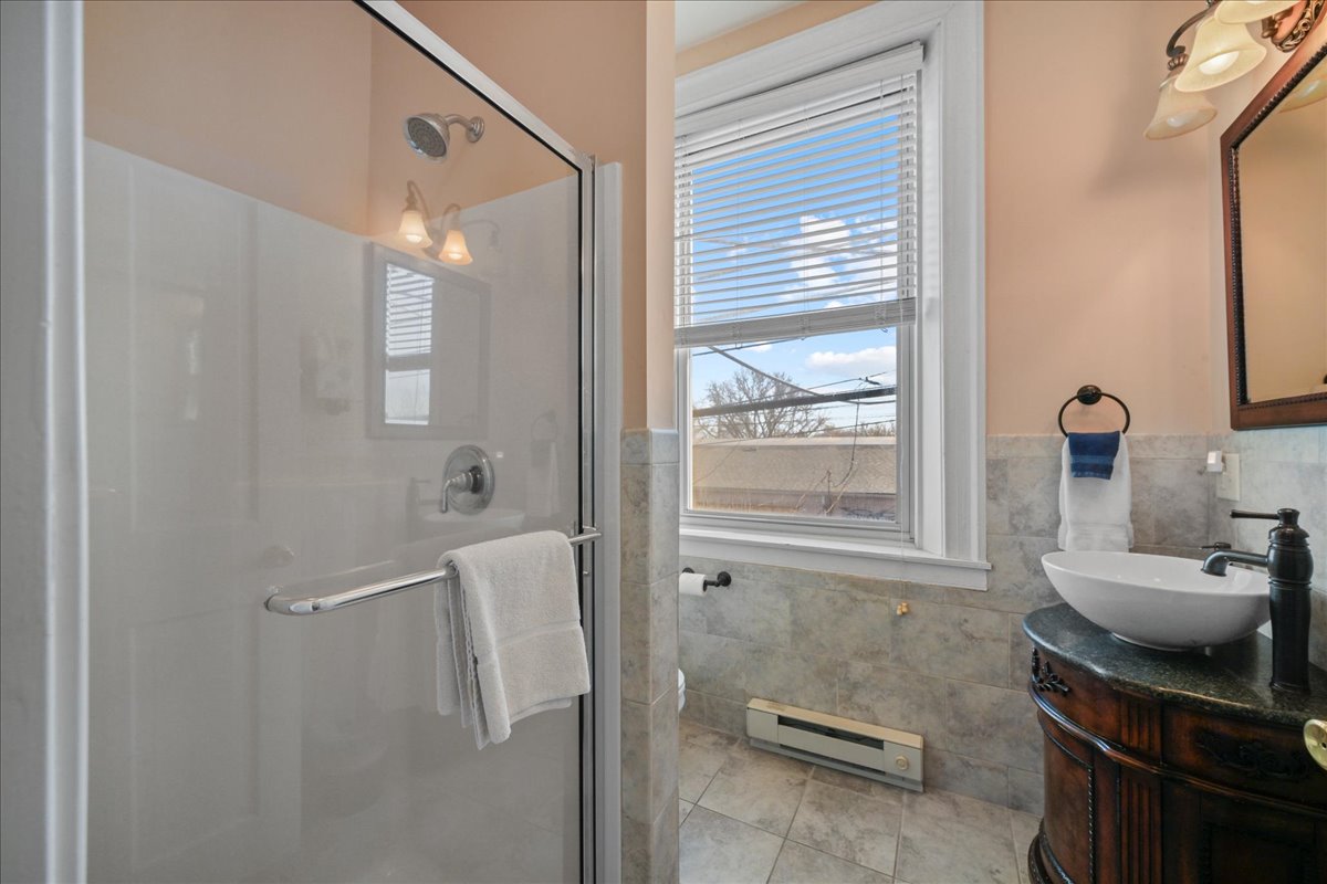 The Southern Spice Chamber bathroom features a walk in shower, an ornate wooden vanity / sink, toilet, and tile floors.
