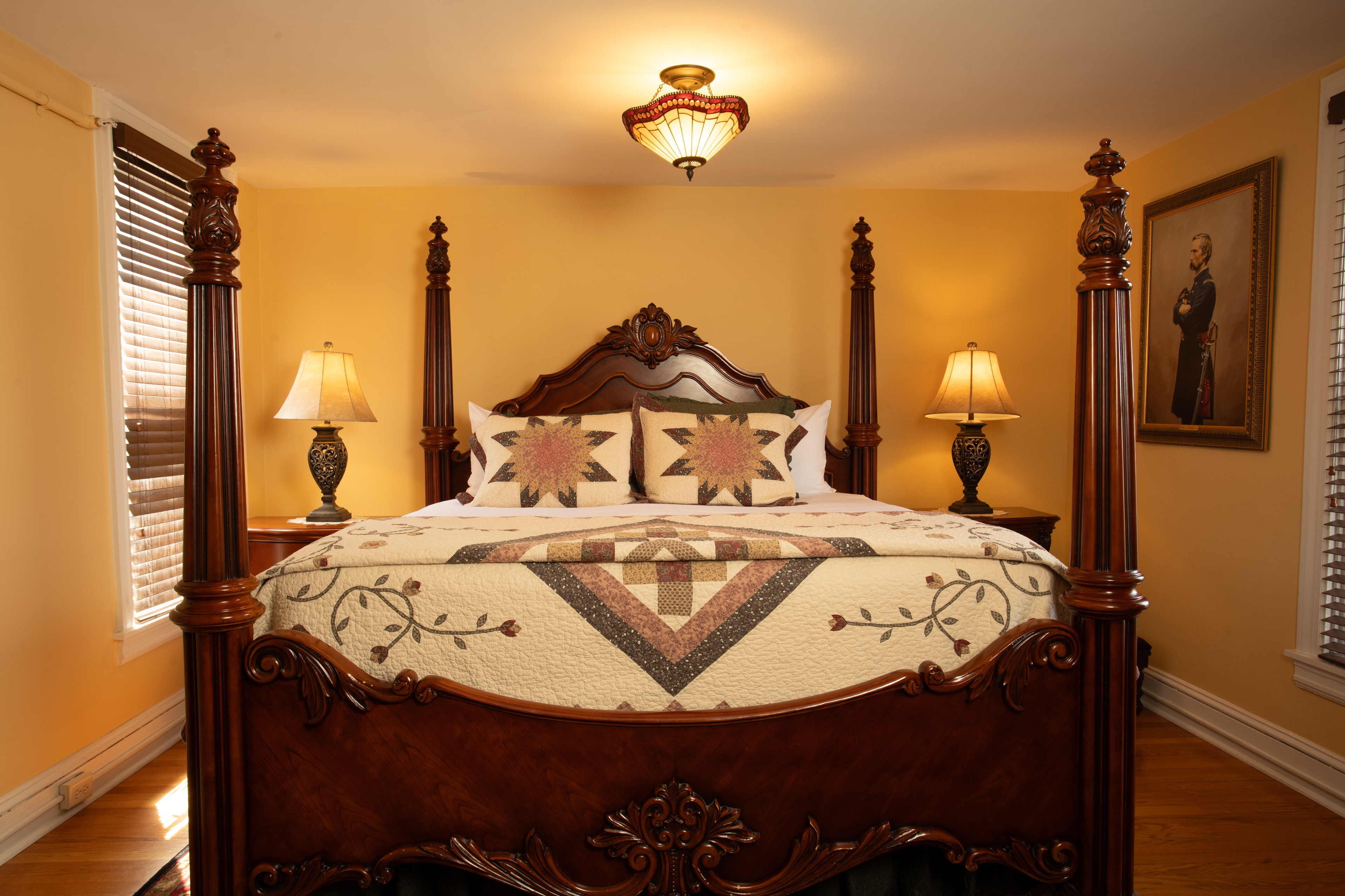 A beautifully furnished bedroom, the Chamberlain, featuring a wooden four-poster bed, decorative quilt, and warm lighting.