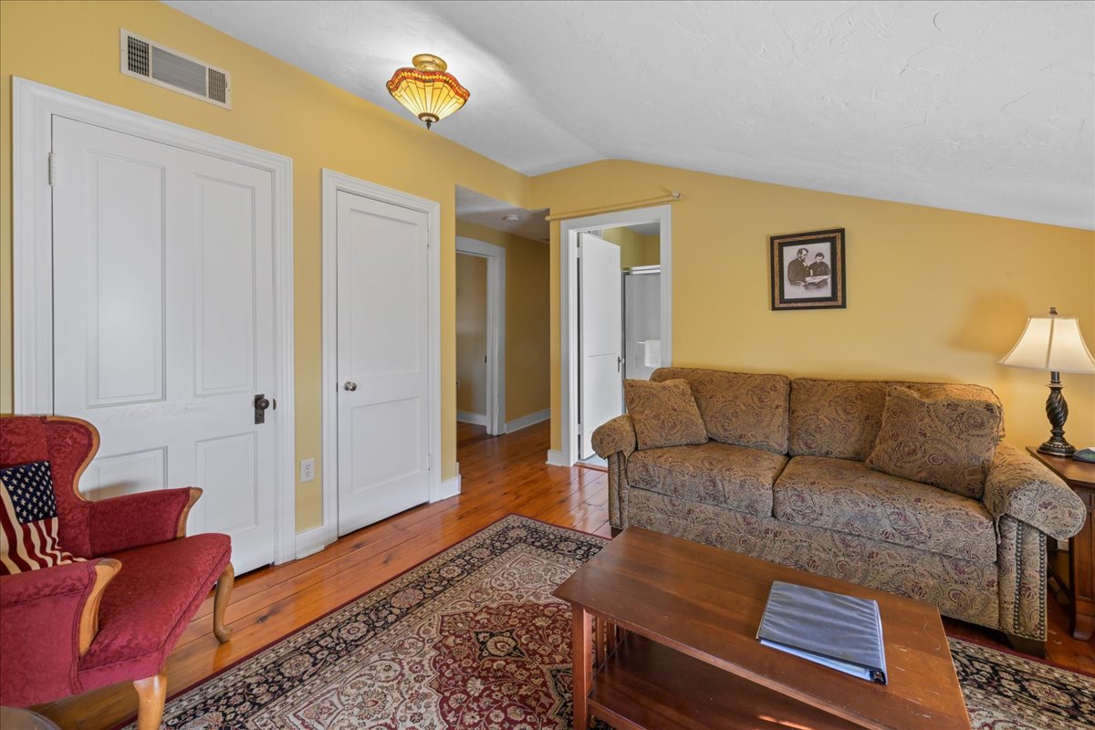 The Lincoln Suite also features a sitting room with a sleeper sofa, a chair, an electric fireplace, TV, and original wooden floors with an area rug.