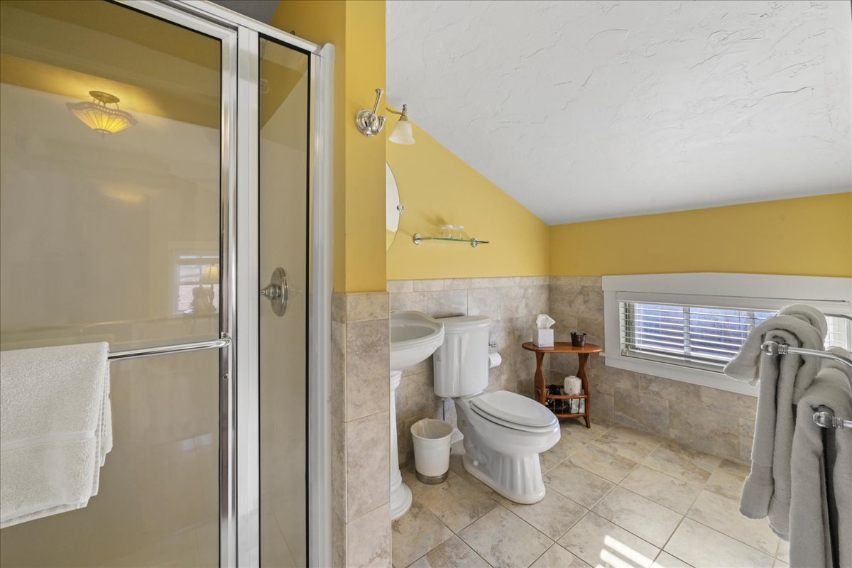 The Lincoln Suite bathroom features a walk-in shower, pedestal sink, toilet, and ceramic tile floors