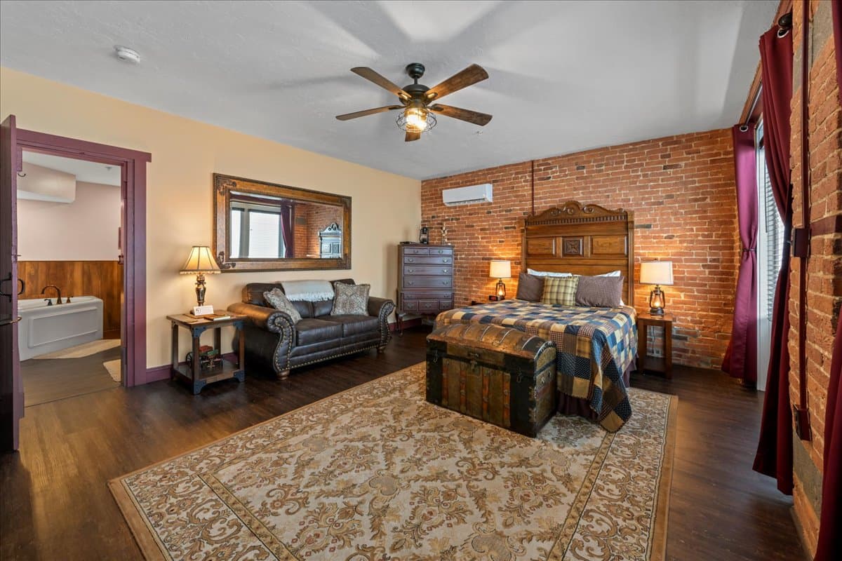 The Carriage House Suite is a ground-level room located in our detatched carriage house.  This room features vinyl plank floors, area rug, a queen size bed with a Victorian head board, 2 night stands with lamps, a leather sofa, a high boy dresser, electric fireplace, a whiskey barrel table, and a split HVAC unit.  This room also has a small refrigerator and a coffee maker.