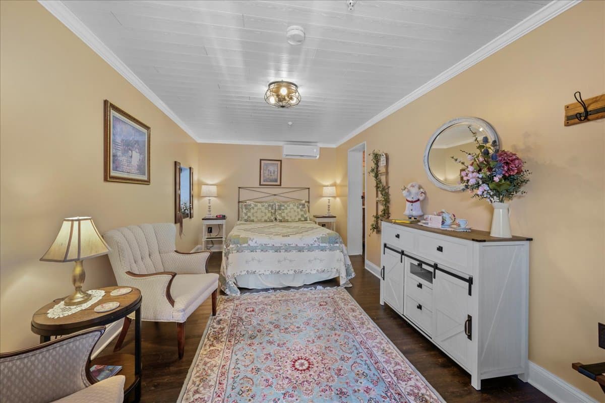 The Garden Chamber is a ground level room located in our detatched carriage house facing the courtyard.  This room features vinyl plank flooring, area rug, a queen size metal bed, 2 night stands with lights, a sitting area with 2 chairs, a dresser, electric stove, and TV.   This room also features a small refrigerator and coffee maker.