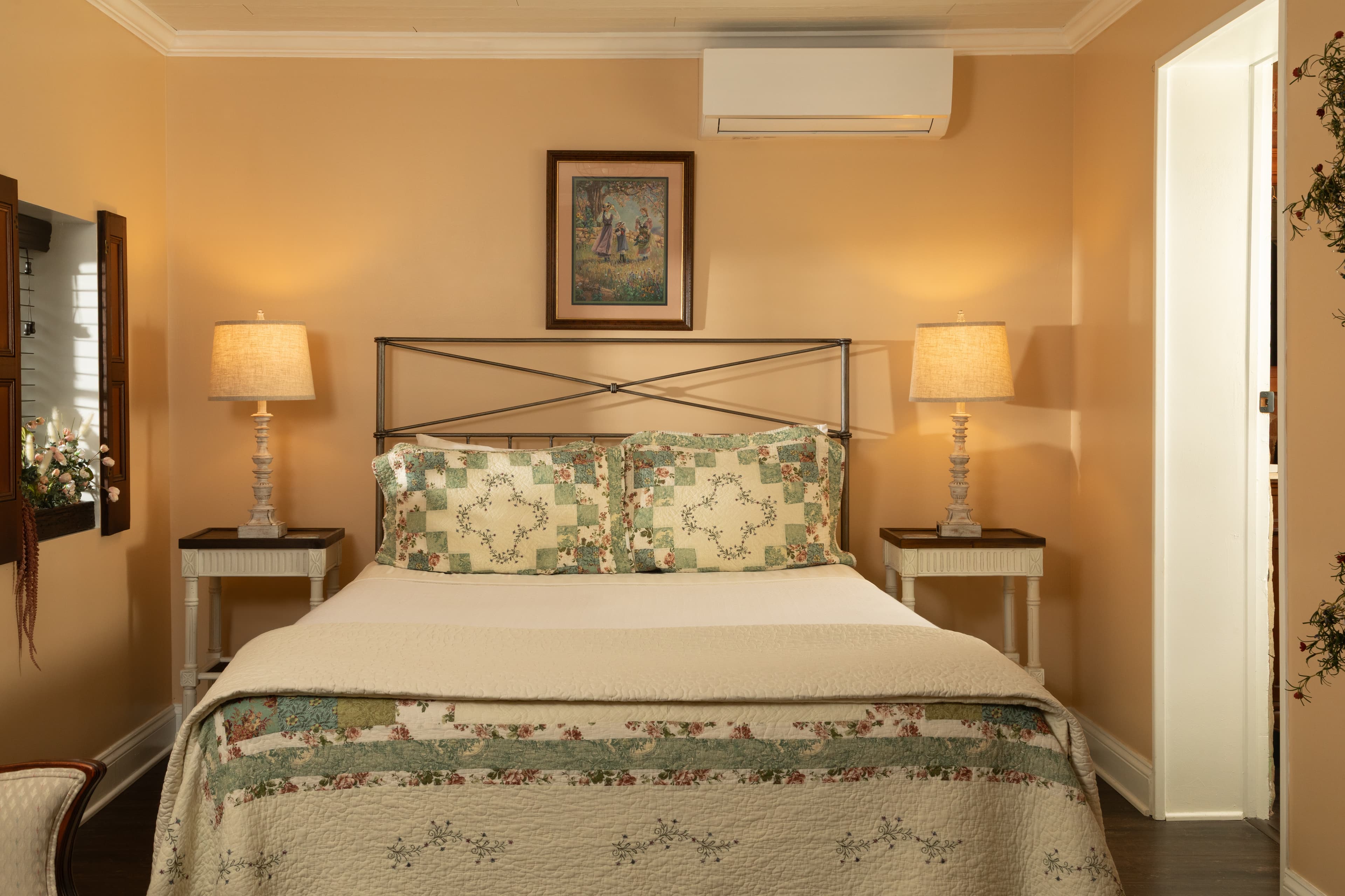 Cozy bedroom with a double bed, decorative pillows, bedside lamps, and warm orange walls.
