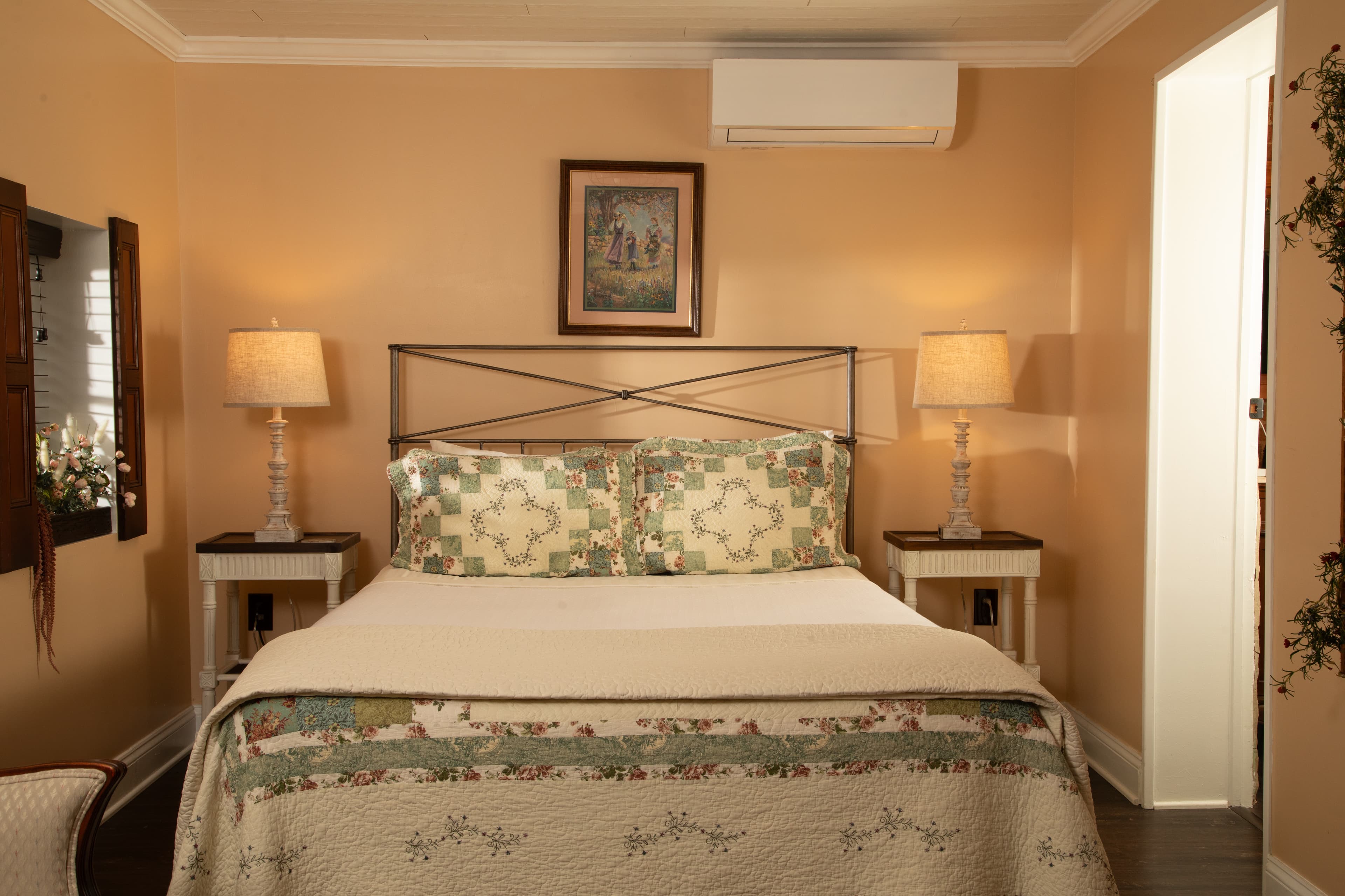 Cozy bedroom with a double bed, decorative pillows, bedside lamps, and warm orange walls.