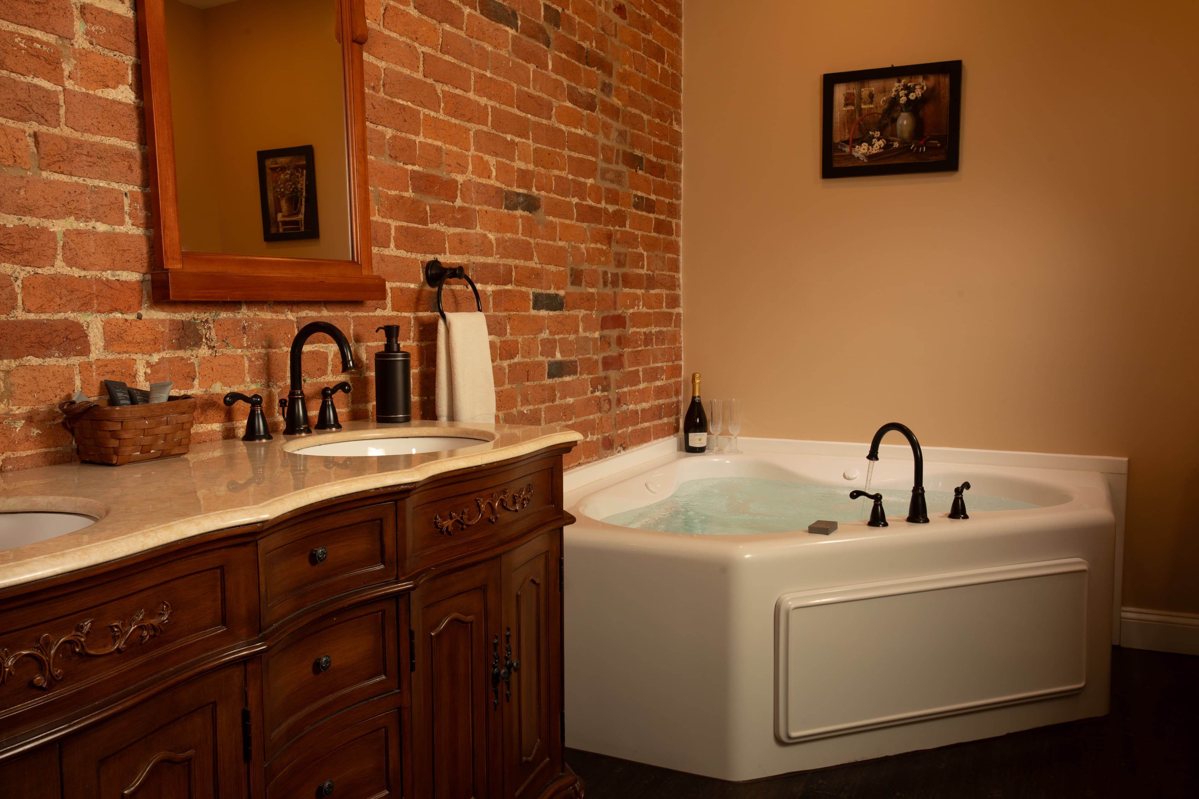 A stylish bathroom featuring a modern jacuzzi tub beside a wooden vanity and brick wall.