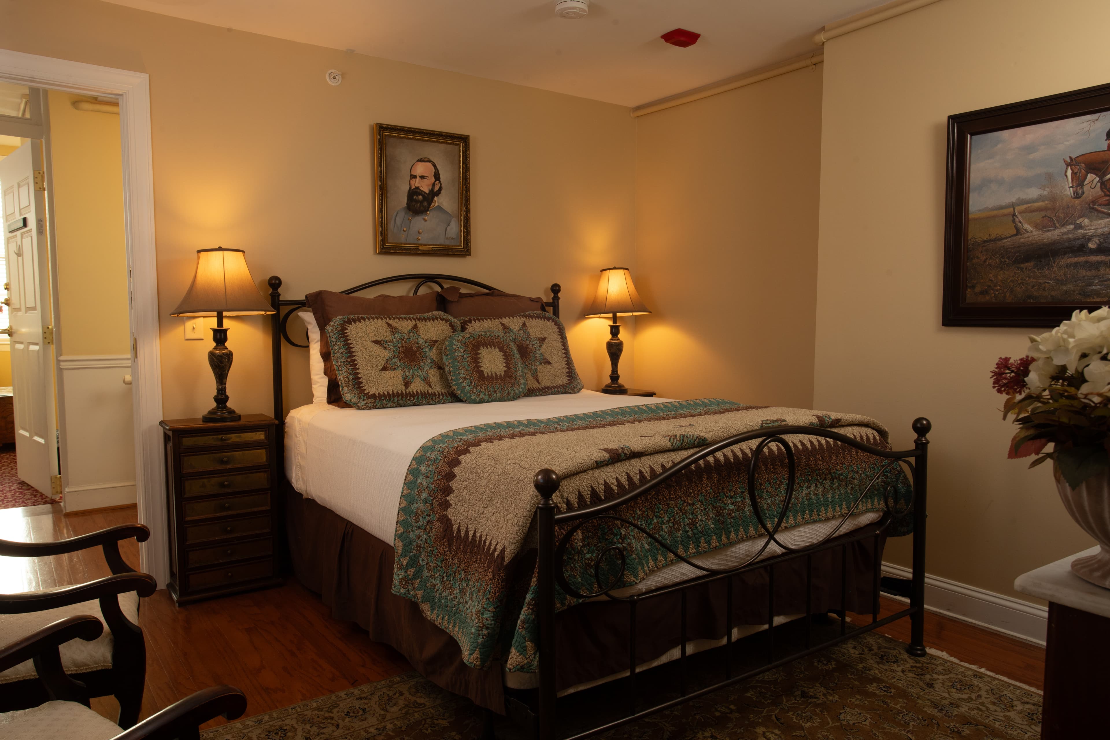 Cozy bedroom featuring a metal bed frame, decorative pillows, vintage lamps, and artwork on the walls.