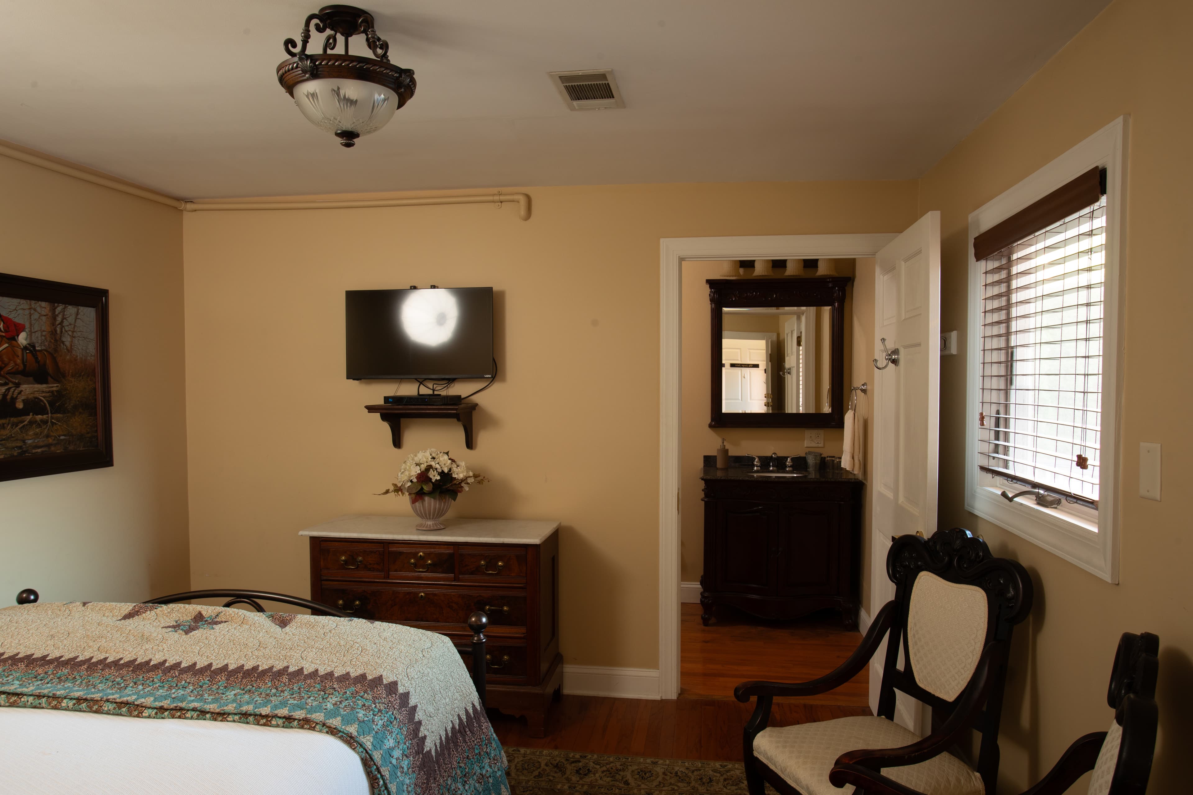 Cozy bedroom with a decorative quilt, television, and adjoining bathroom.