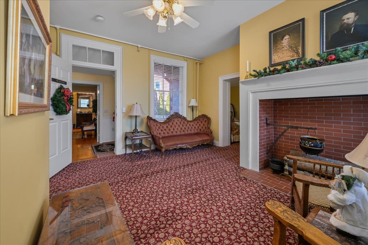 The Swope Suite with two queen-size beds, patterned bedspreads, and wooden nightstands flanking the beds. The walls are light yellow, and the carpet is a red patterned design.
