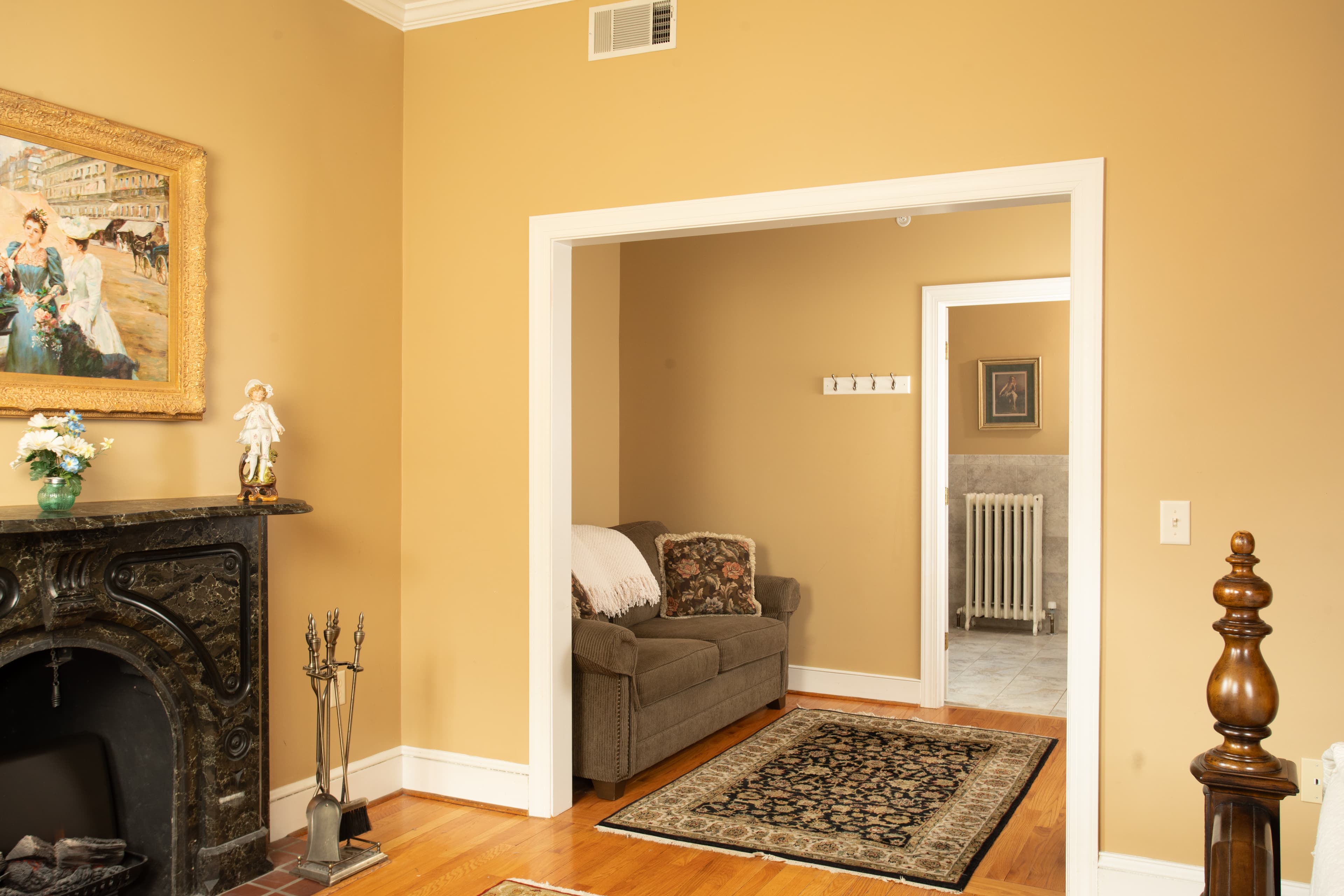 A cozy living room featuring a gray sofa, decorative artwork, and a patterned rug, with doorways leading to adjacent spaces.