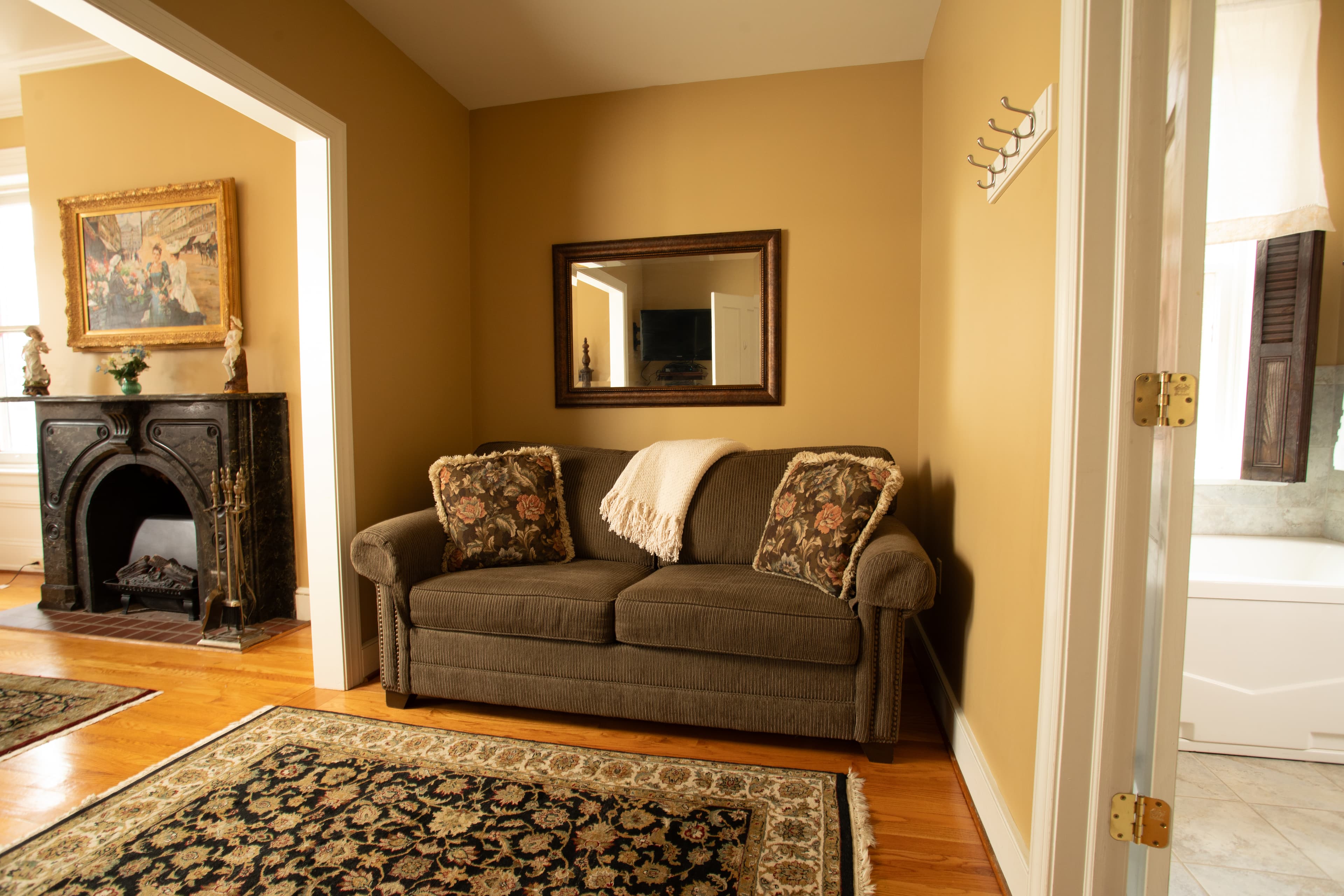 Cozy living room featuring a sofa with floral cushions, a decorative mirror, and a fireplace.