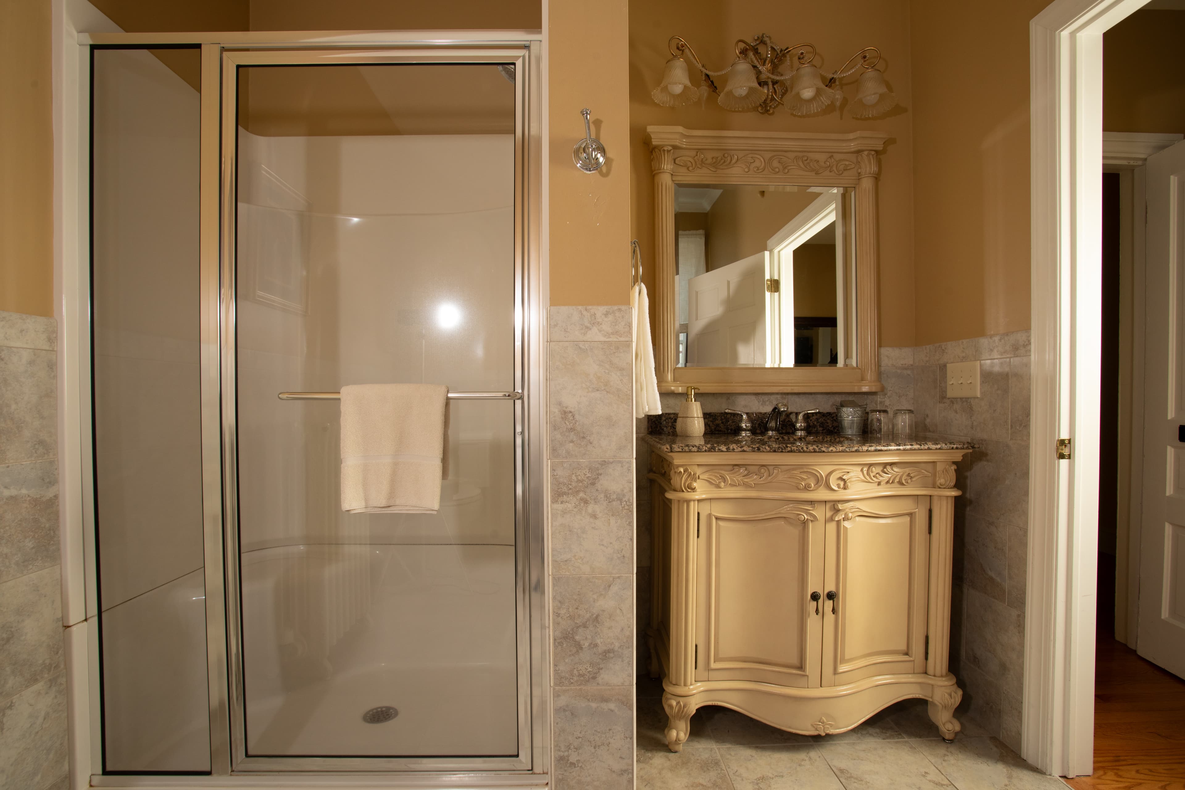 A luxurious bathroom with a glass shower, ornate mirror, and decorative vanity.