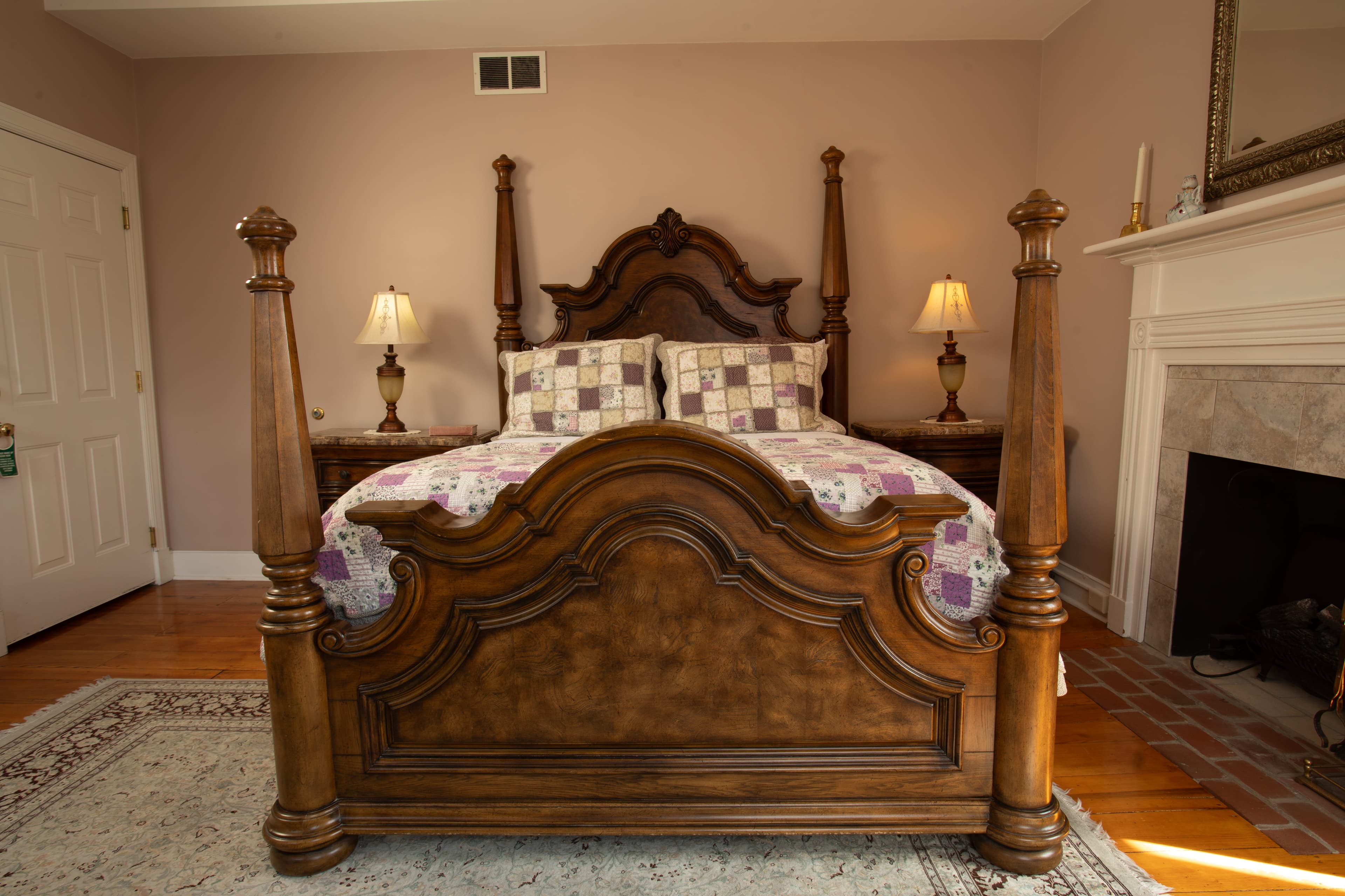 A classic wooden bed with ornate posts and a quilt, set against a softly colored wall in a cozy bedroom.
