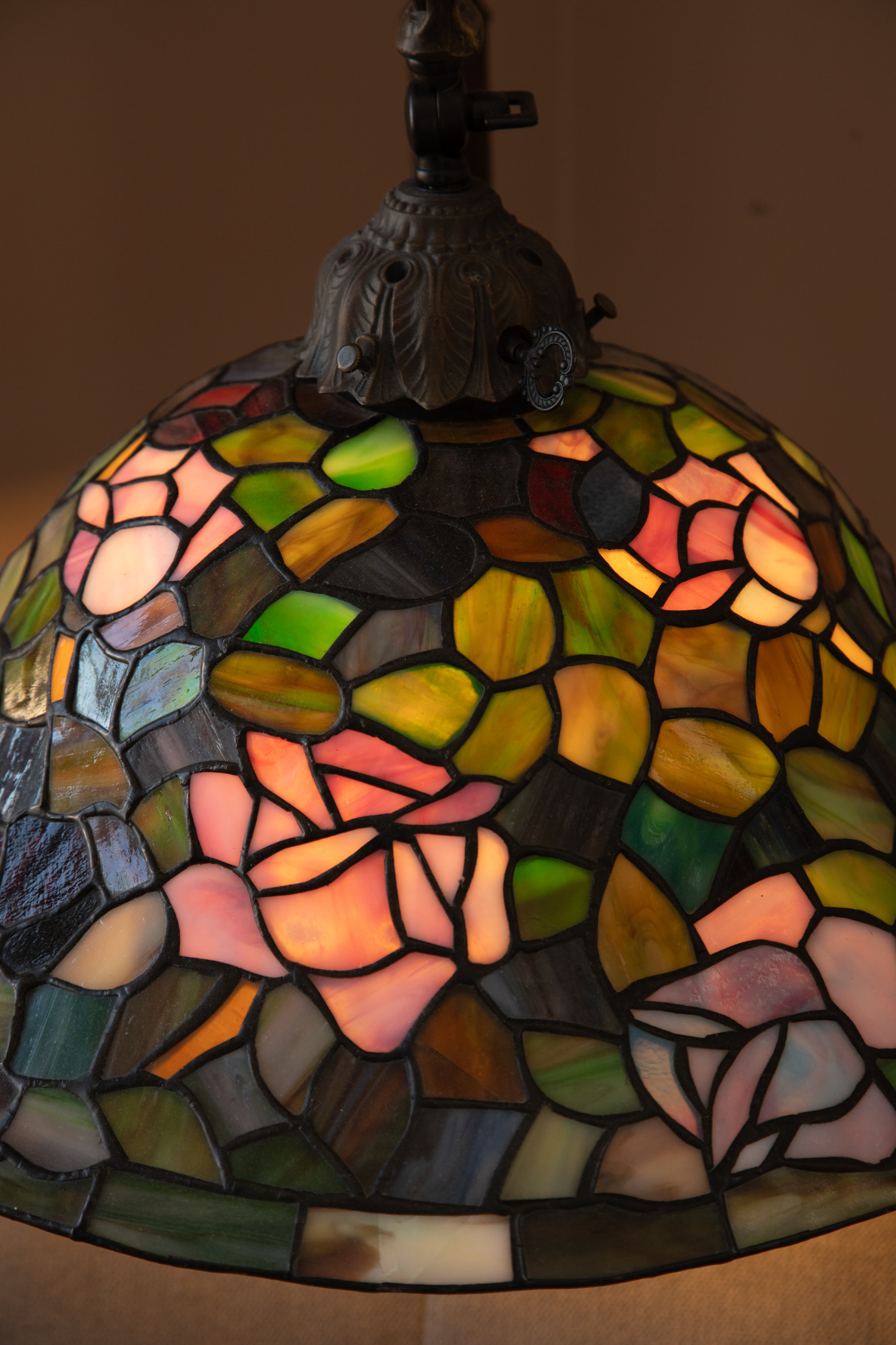 A close-up of a stained glass lamp shade featuring floral patterns in various colors.
