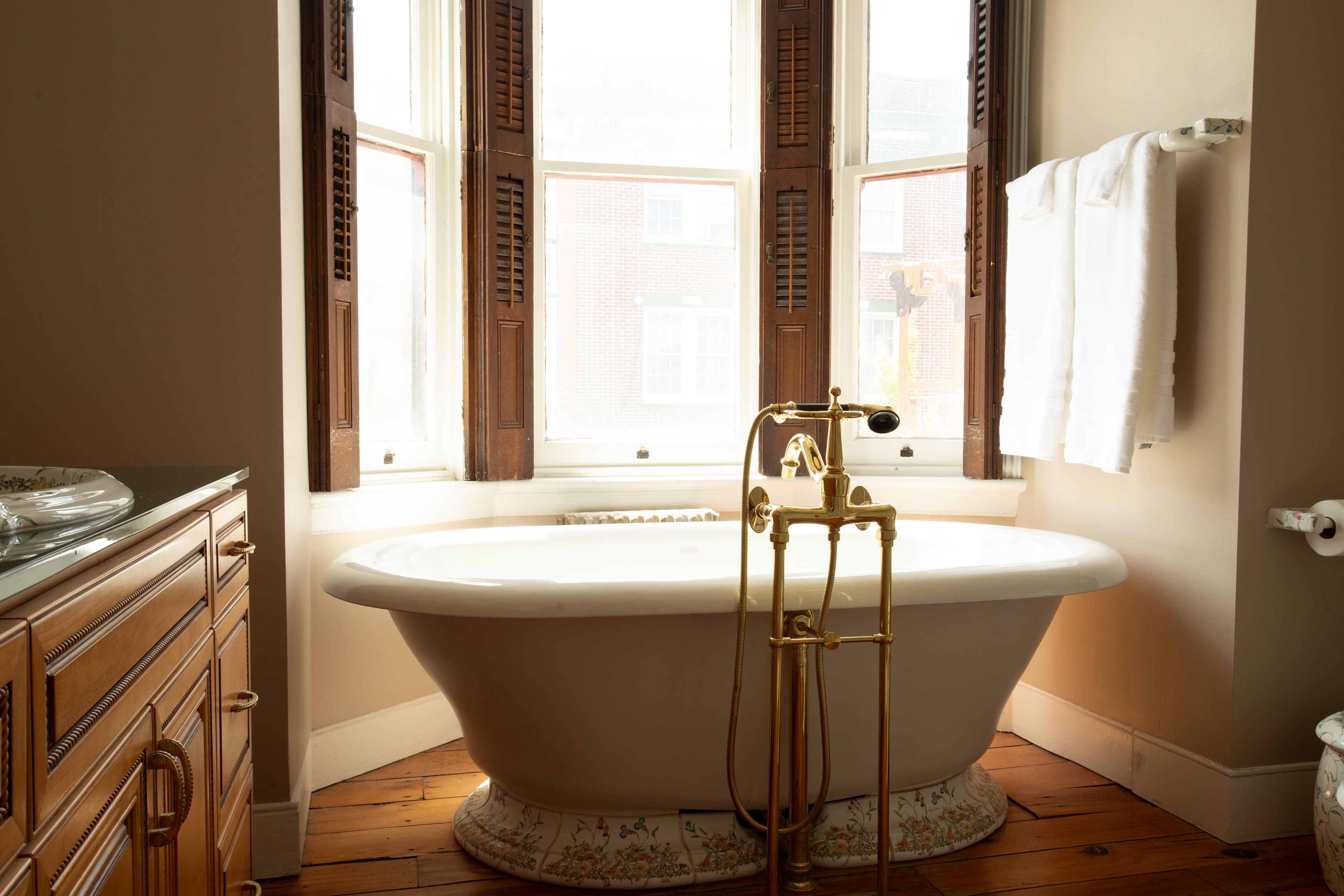 A bright bathroom featuring a vintage freestanding bathtub and wooden window shutters.
