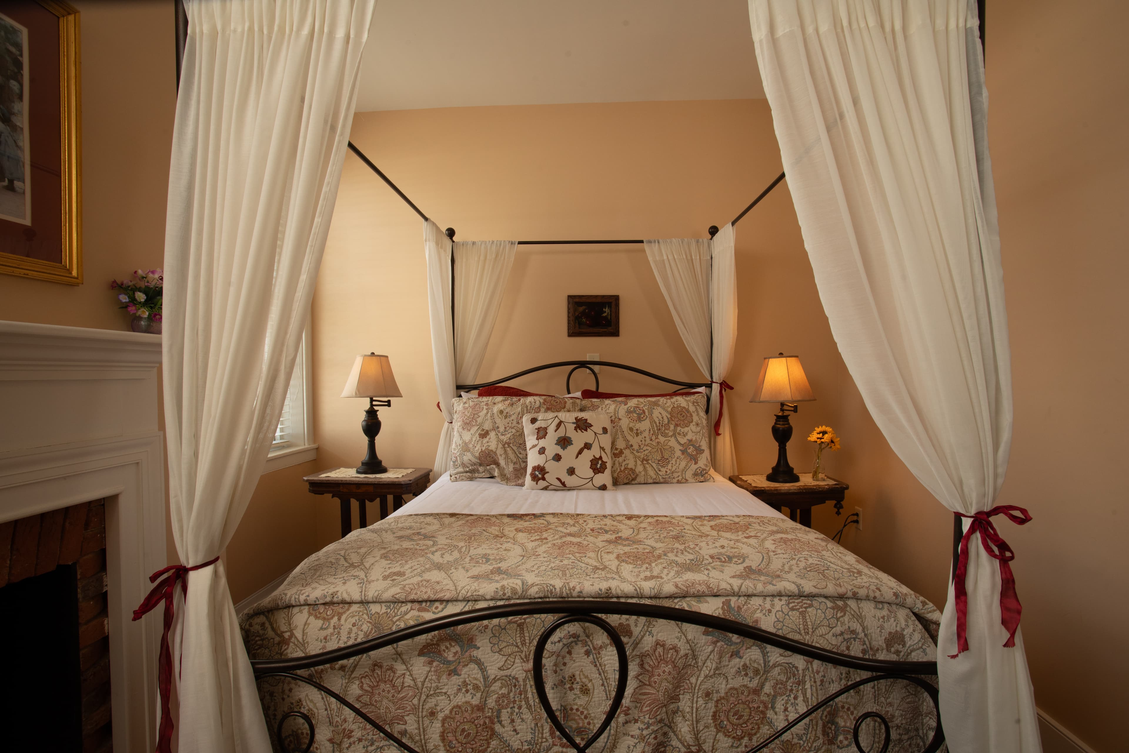 A cozy four-poster bed with decorative bedding and bedside lamps in a welcoming room.