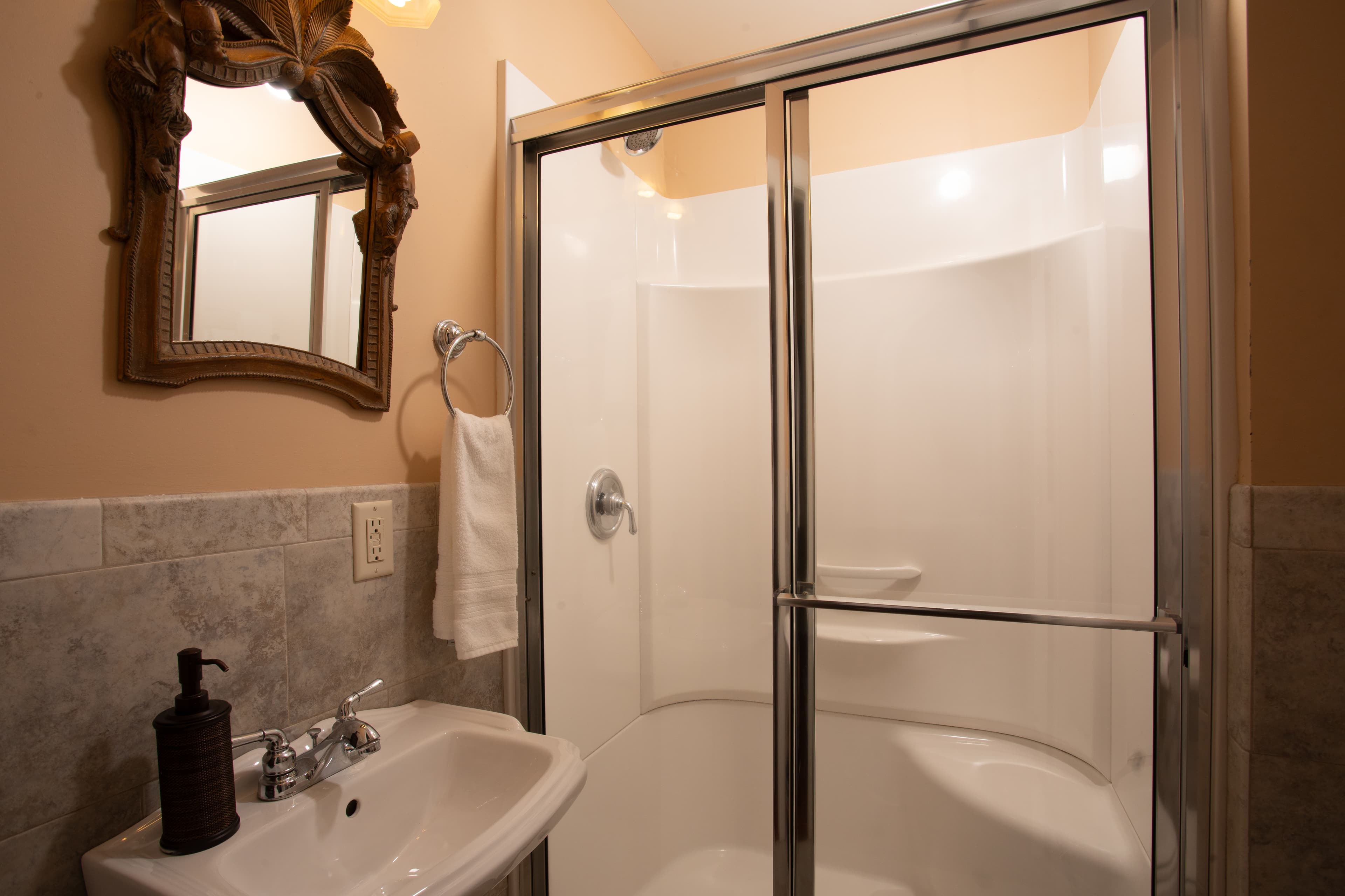 A bathroom featuring a glass-enclosed shower, a mirror, and a sink with soap.