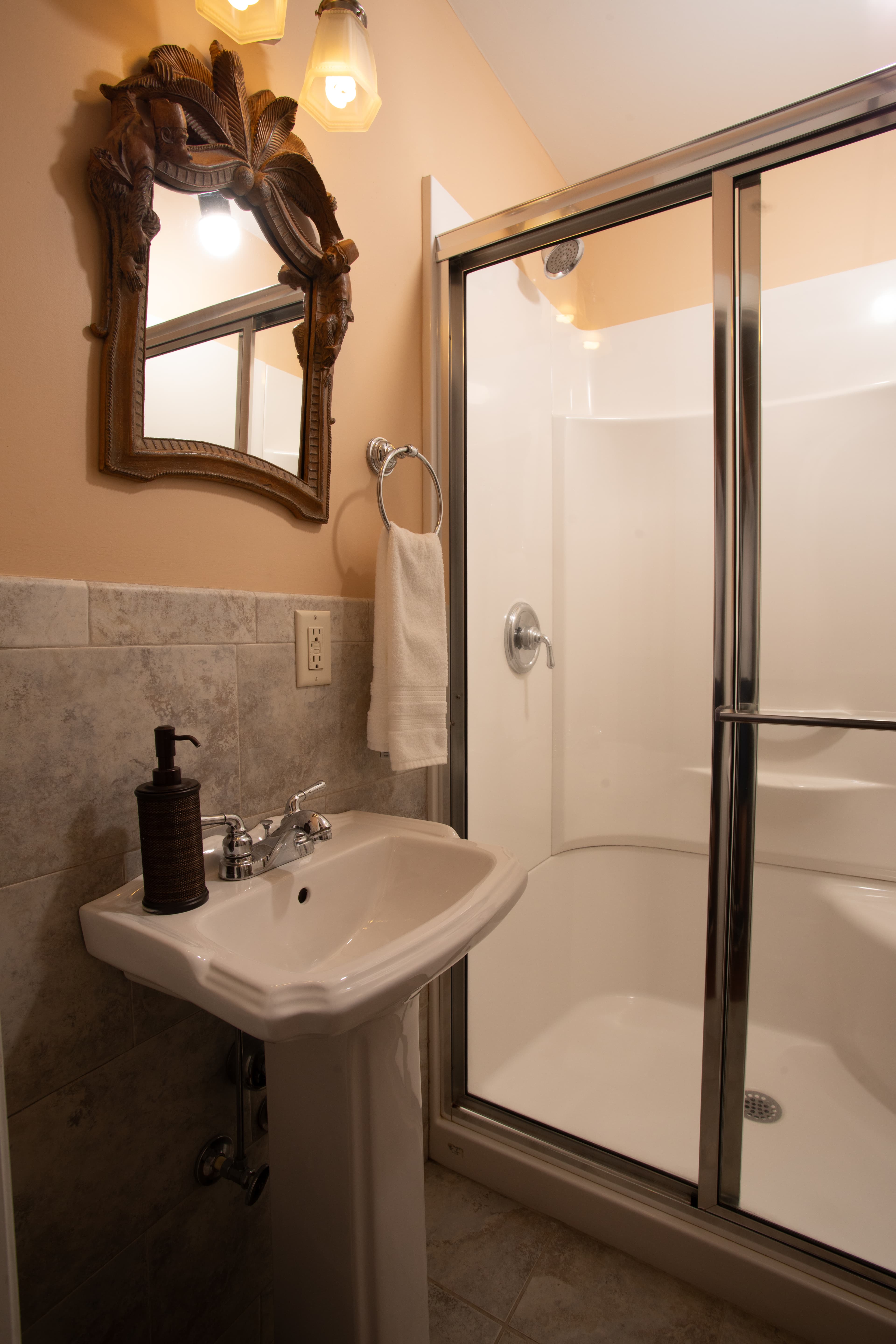 A small bathroom featuring a pedestal sink and a glass-enclosed shower stall.