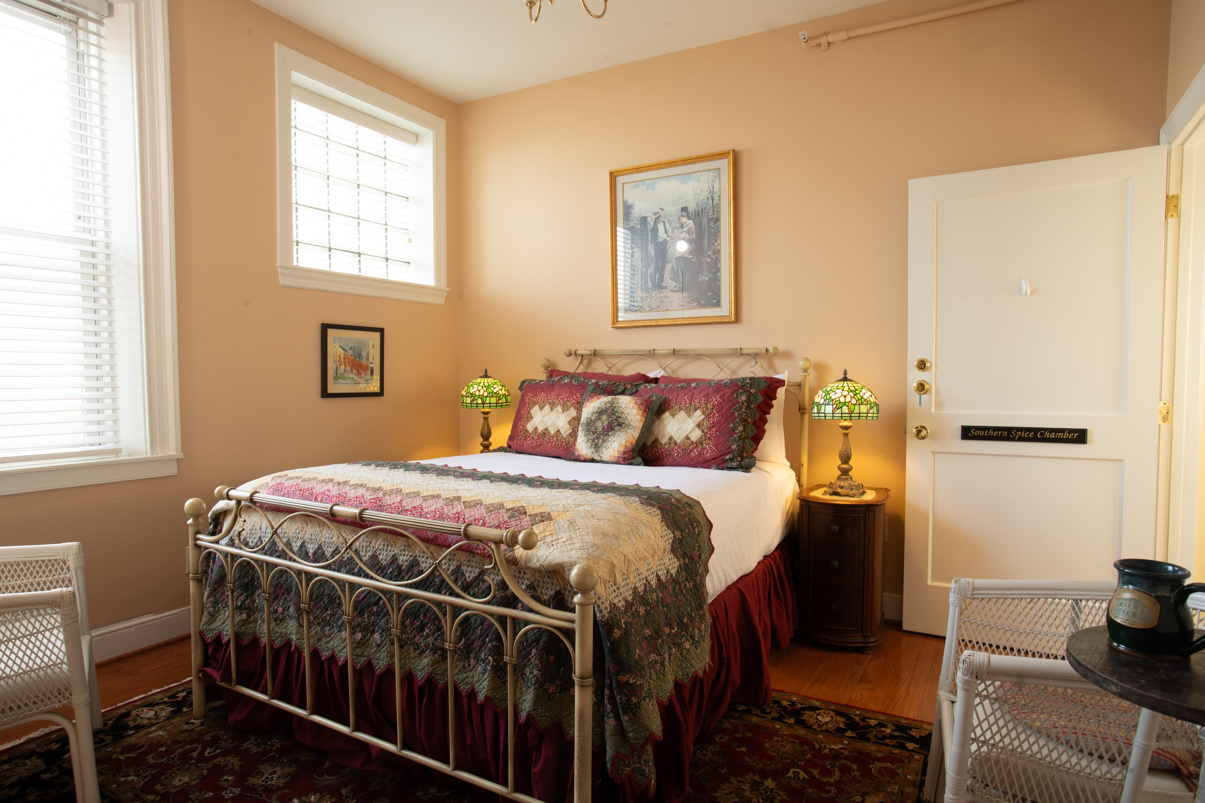 A cozy bedroom featuring a metal bed, decorative bedding, and stylish lamps, with soft lighting and warm tones.
