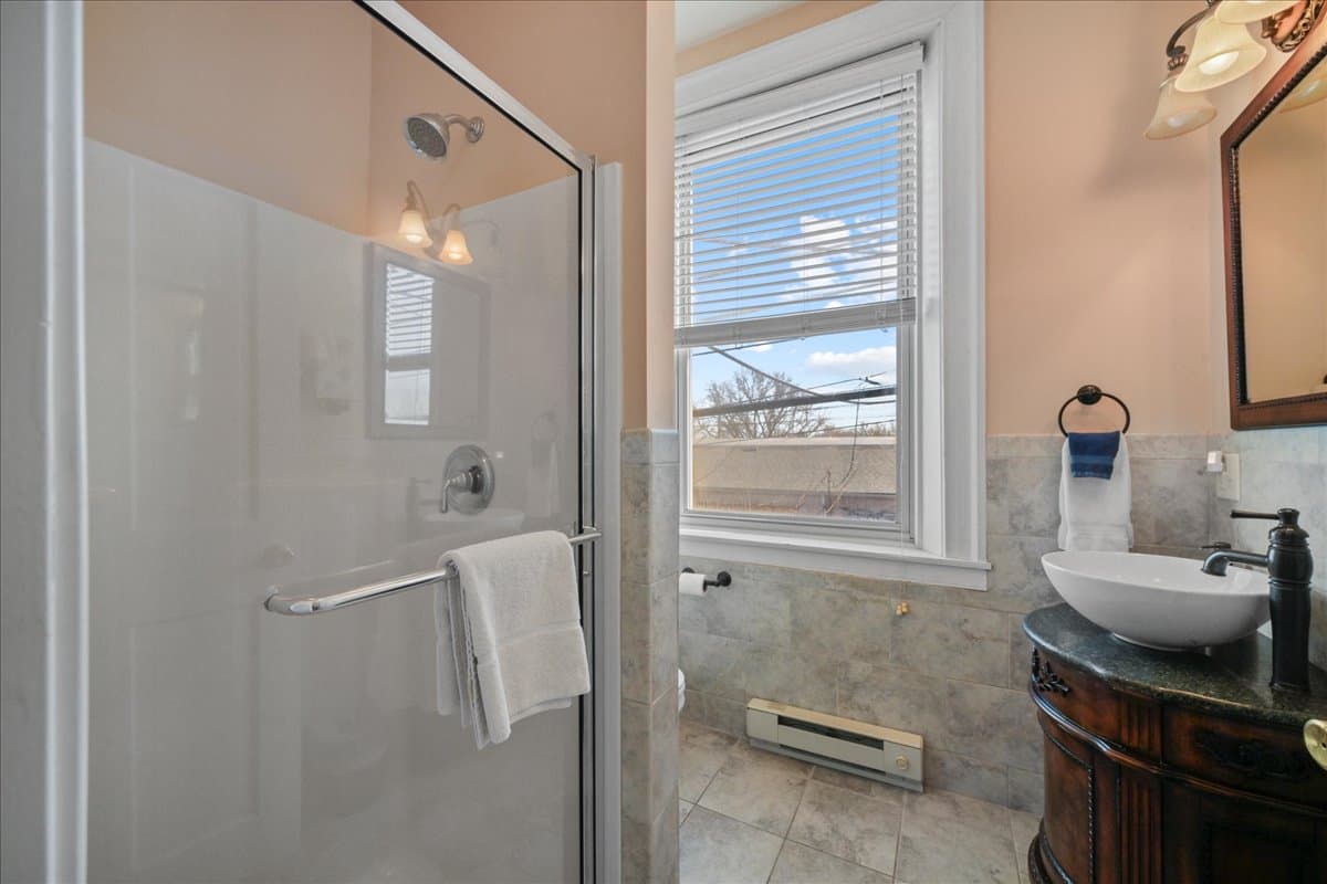 The Southern Spice Chamber bathroom features a walk in shower, an ornate wooden vanity / sink, toilet, and tile floors.