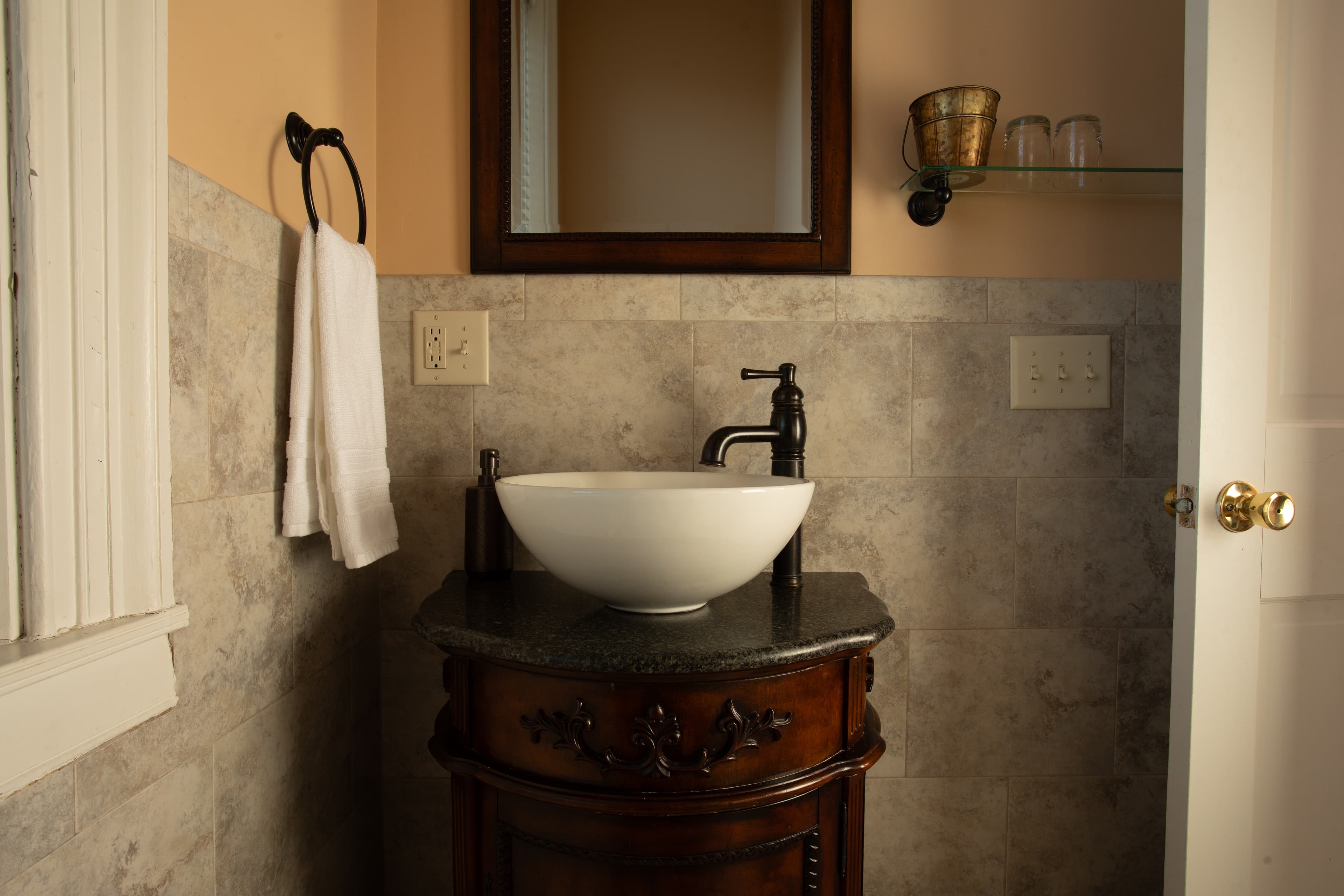 A modern bathroom sink with a bowl-shaped basin and wooden cabinet under a mirror.