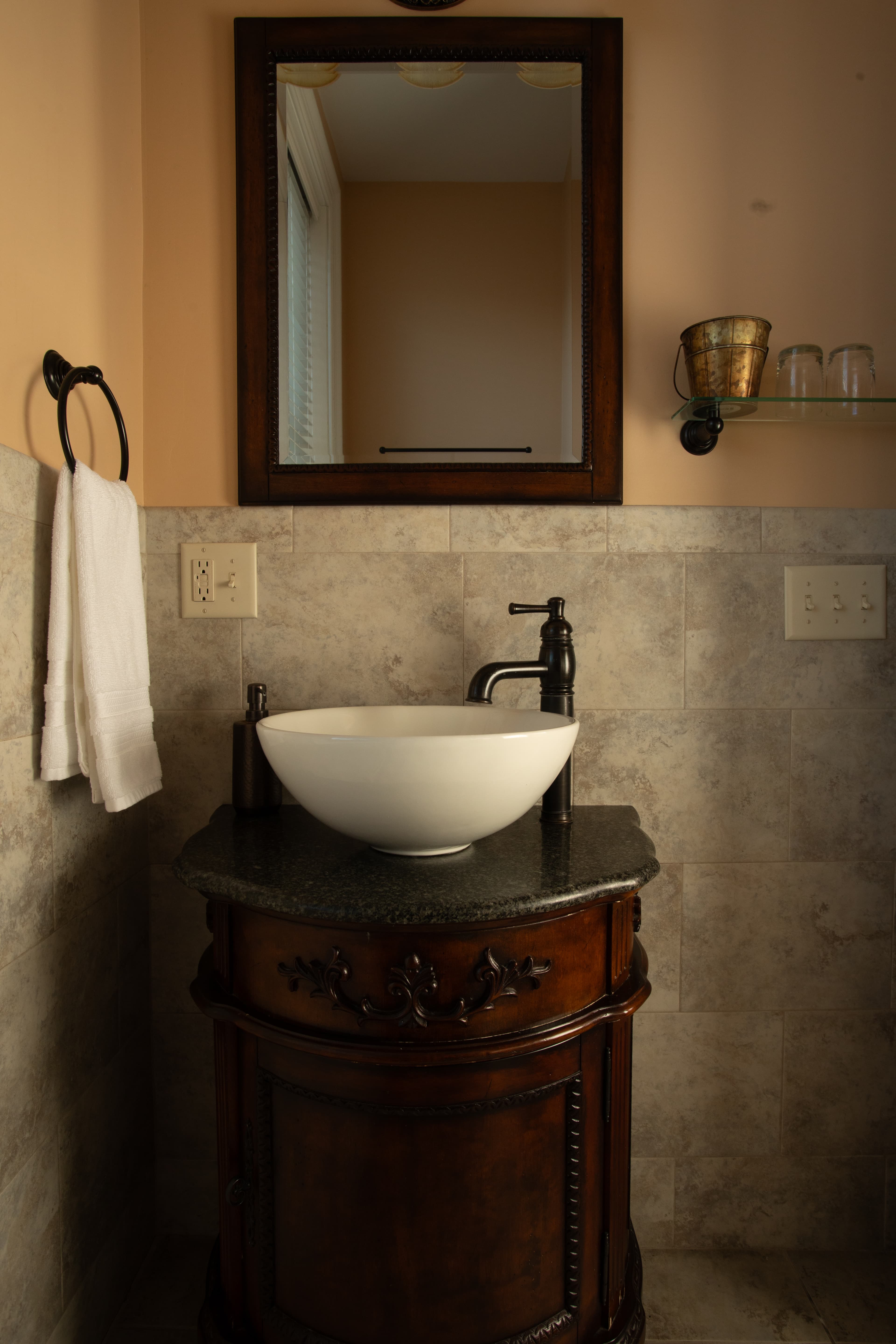 A stylish bathroom vanity features a round sink and a large mirror above.