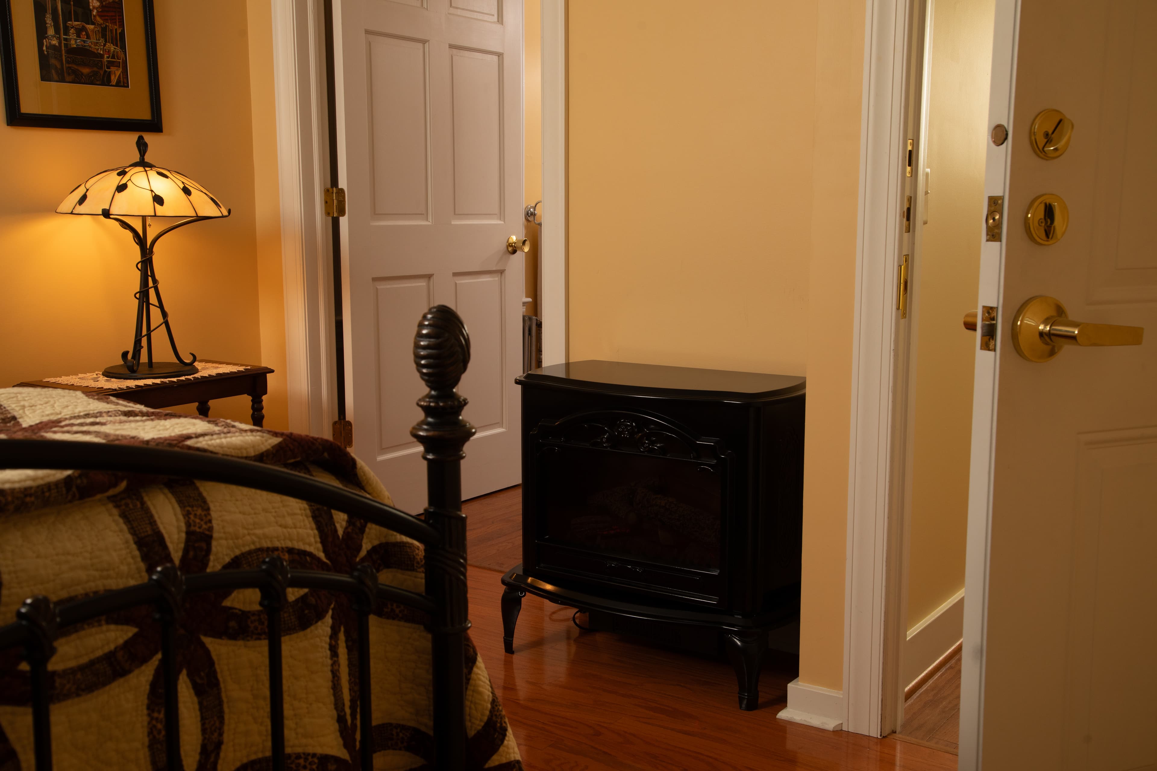 A warm, inviting room featuring a lamp, a black heater, and doorways leading to other rooms.