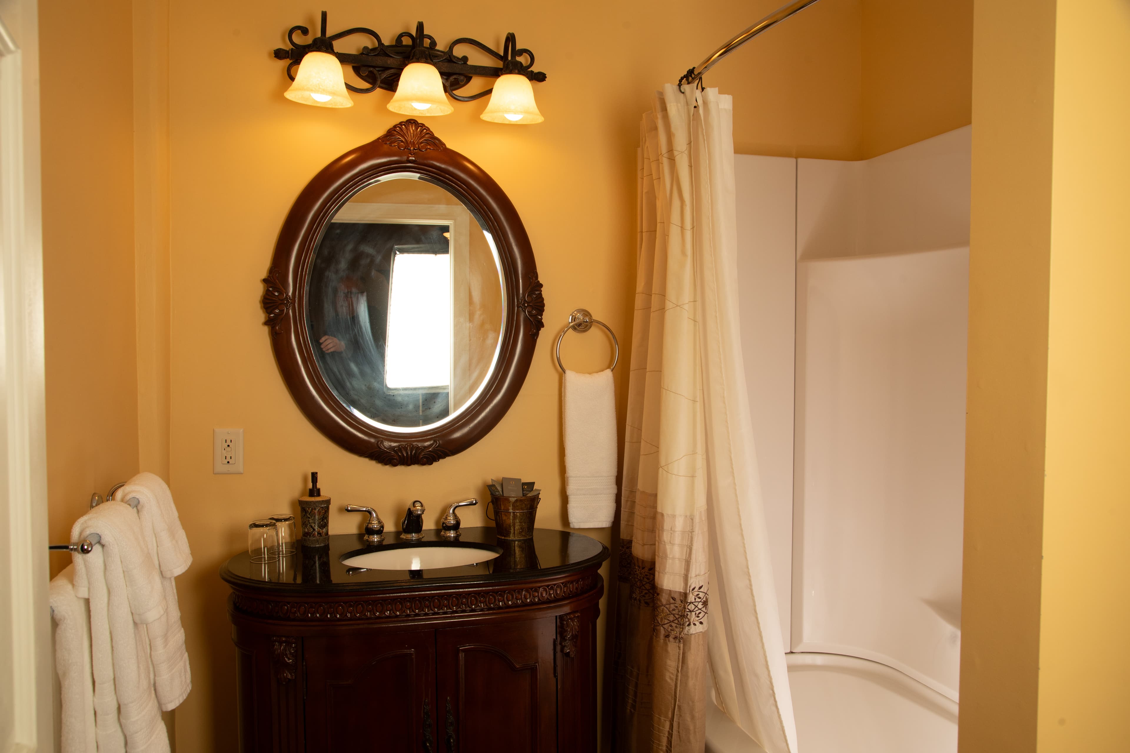 A cozy bathroom featuring a dark wood vanity, round mirror, and a shower with a curtain.