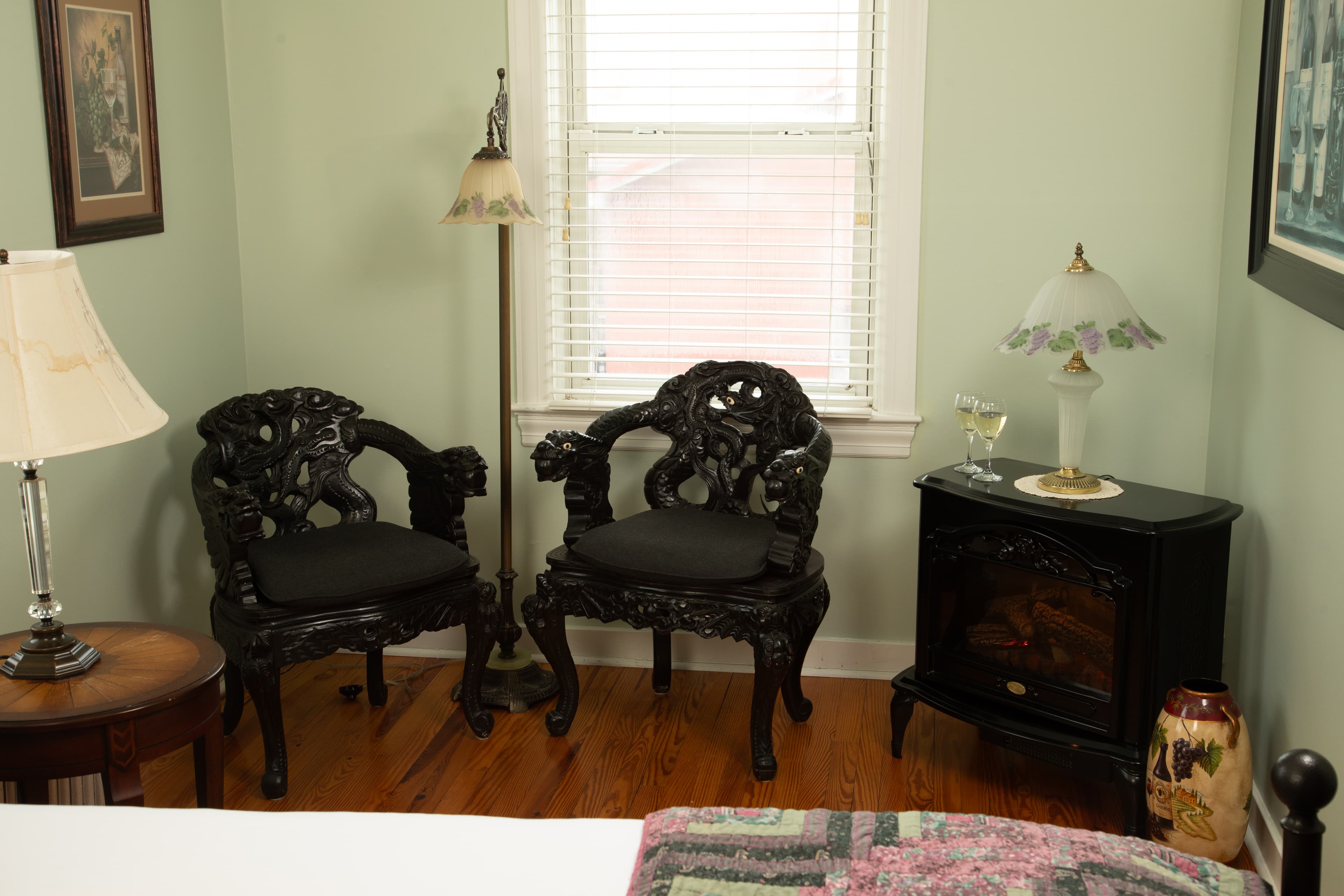 A cozy corner in the Cabernet Chamber featuring two ornate black chairs, a small black table with a lamp, and a warm ambiance.