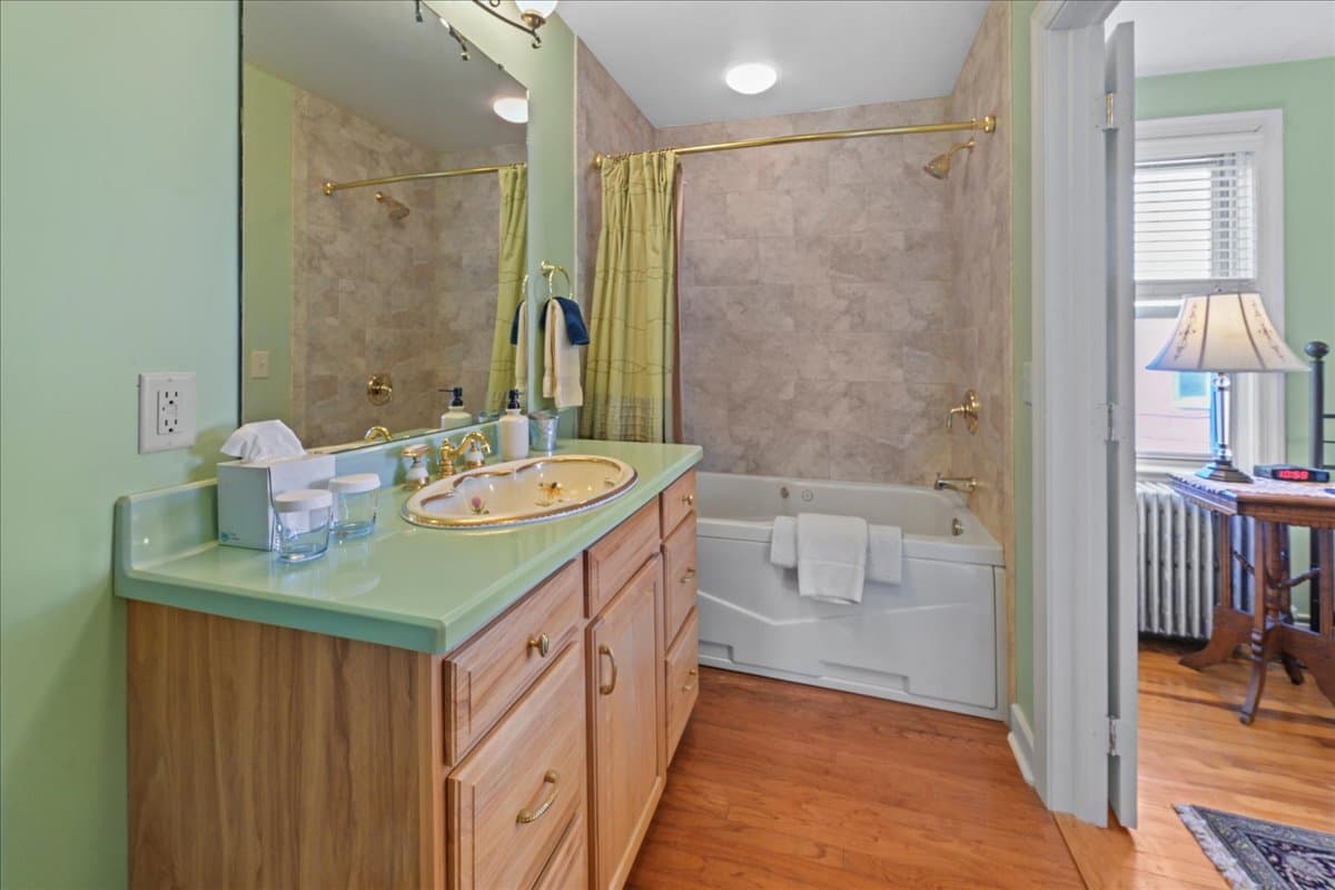 The Cabernet Chamber bathroom with ornate marble sink and jetted tub / shower combo.