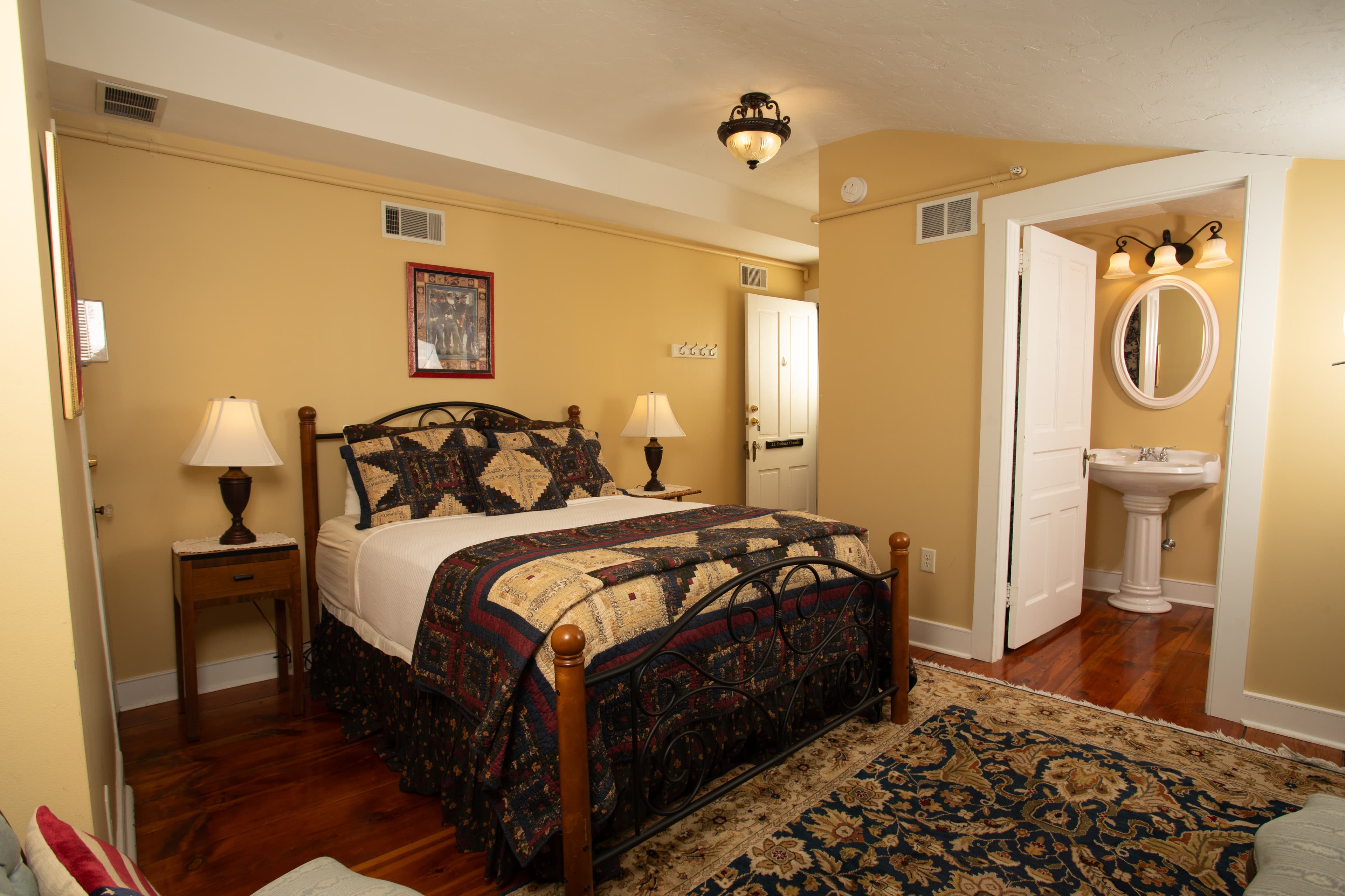 A cozy bedroom featuring a wooden bed, lamps, and an adjoining bathroom.