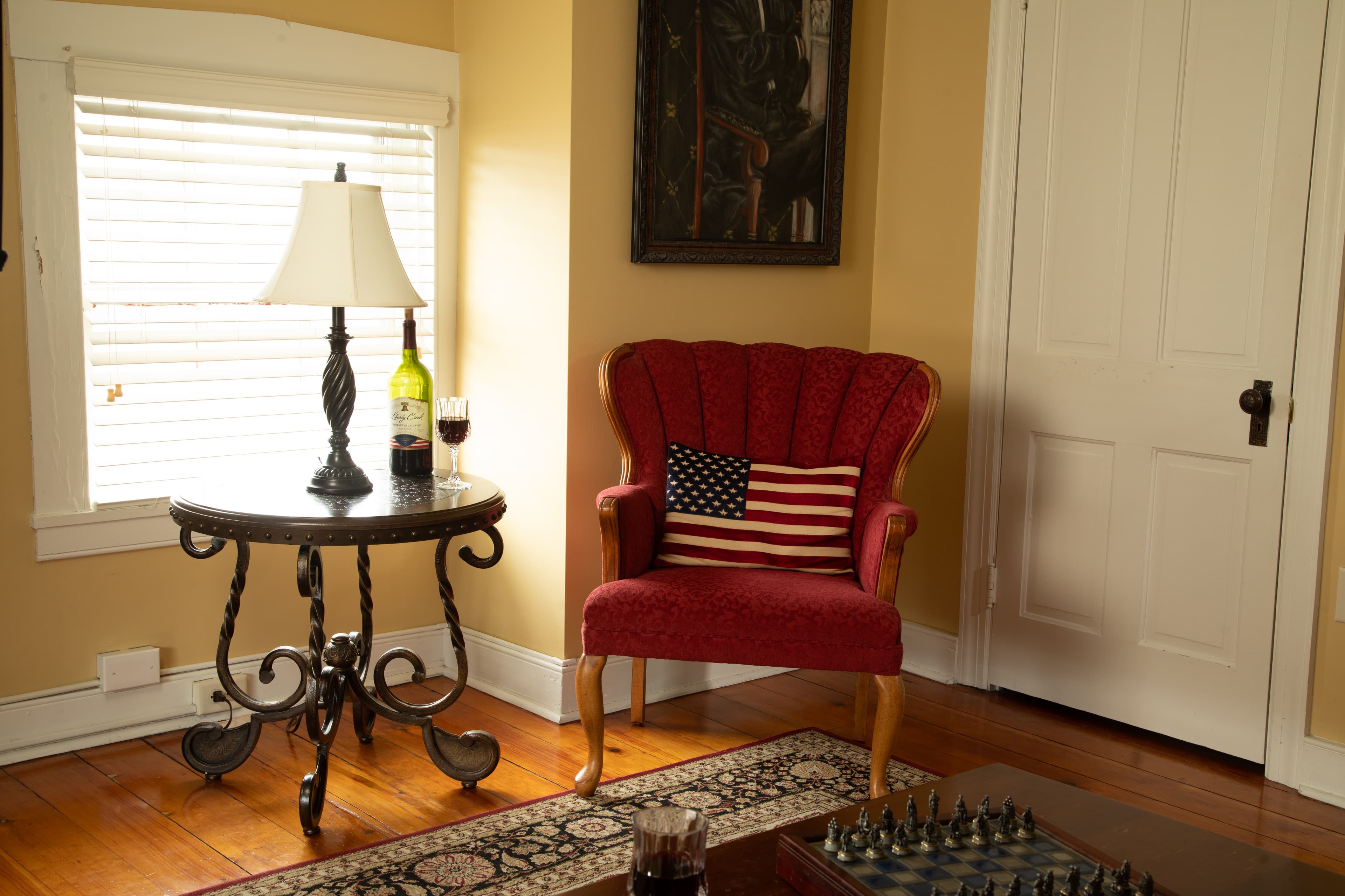 The Lincoln Suite also features a sitting room with a sleeper sofa, a chair, an electric fireplace, TV, original wooden floors with an area rug.