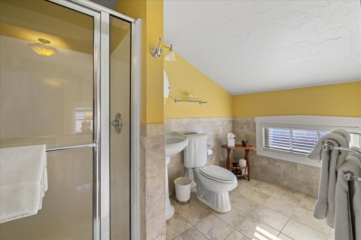 The Lincoln Suite bathroom features a walk-in shower, pedestal sink, toilet, and ceramic tile floors