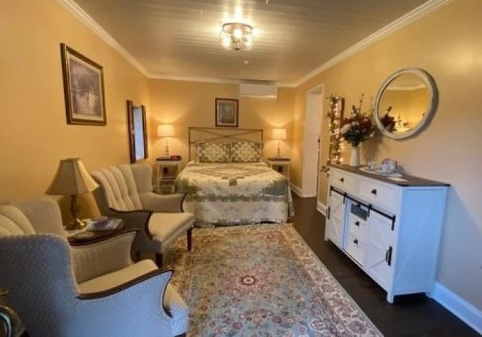 The Garden Chamber is a ground level room located in our detatched carriage house facing the courtyard.  This room features vinyl plank flooring, area rug, a queen size metal bed, 2 night stands with lights, a sitting area with 2 chairs, a dresser, electric stove, and TV.   This room also features a small refrigerator and coffee maker.