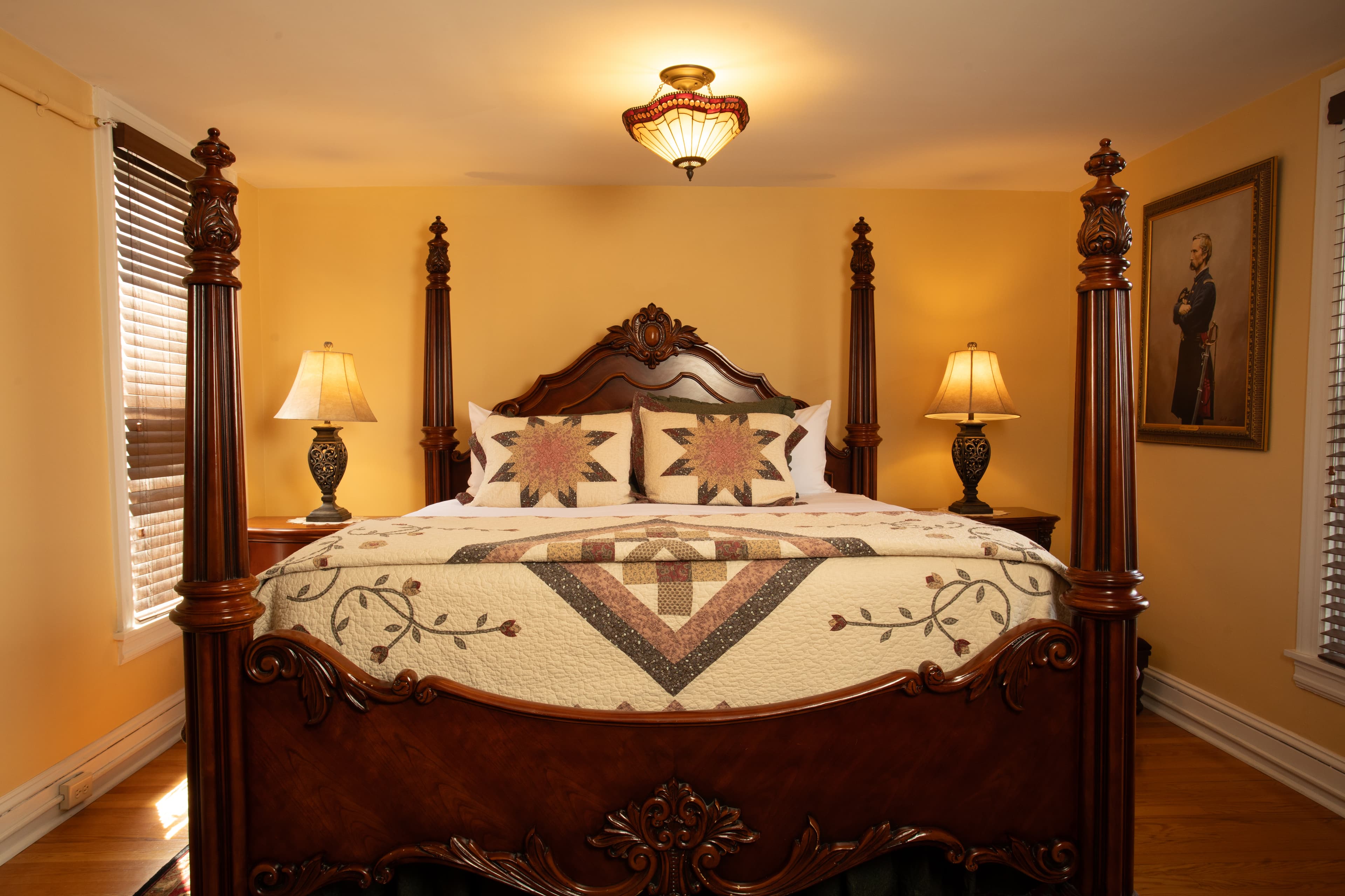A beautifully furnished bedroom, the Chamberlain, featuring a wooden four-poster bed, decorative quilt, and warm lighting.
