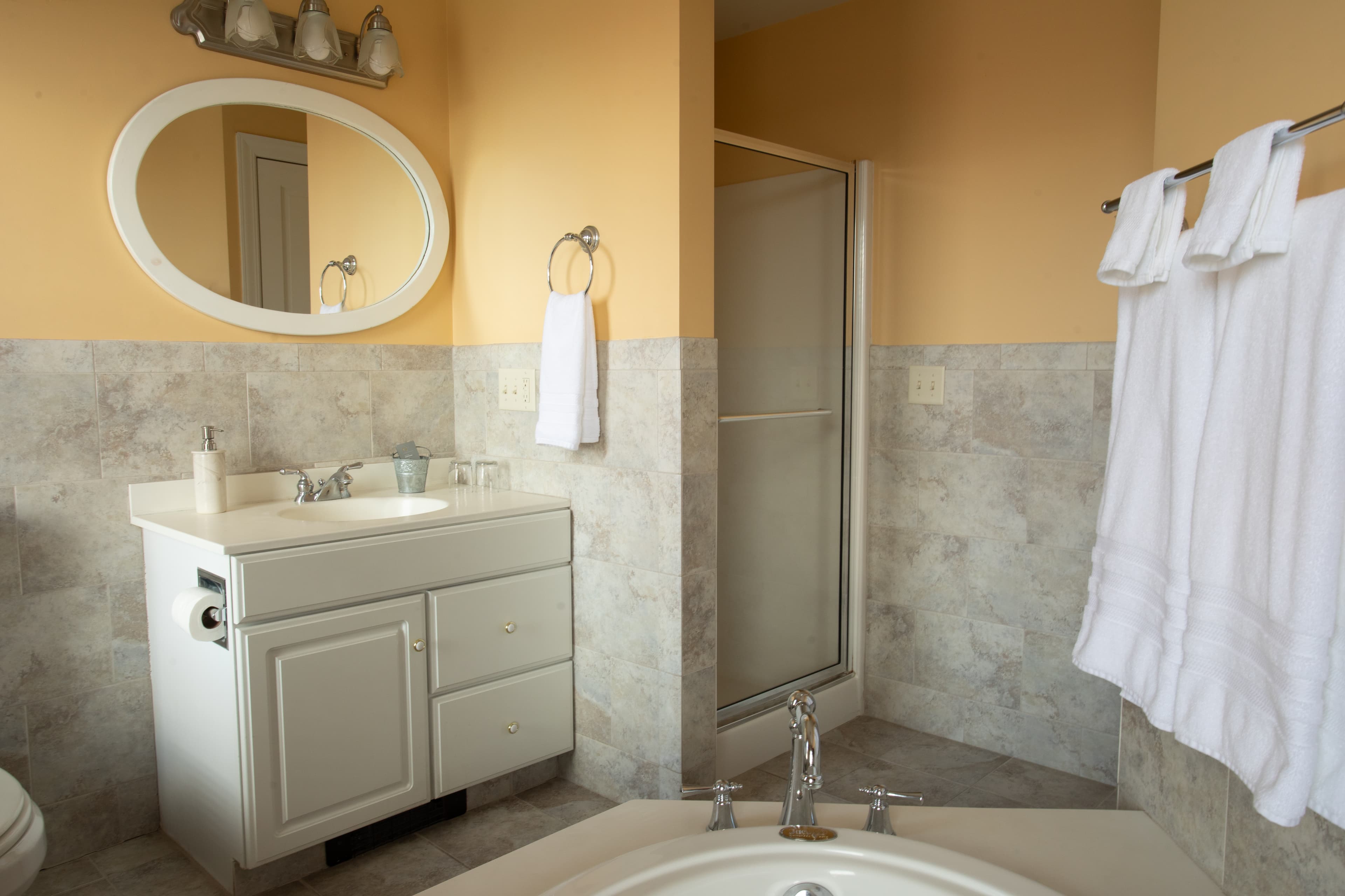Bright bathroom in the Chamberlain featuring a white vanity, shower, and elegant towels.
