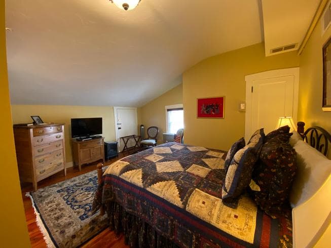 The Lt. Pohlman Chamber features a queen-size metal bed, dresser, TV, and 2 chairs.