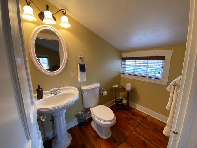 The Lt. Pohlman Chamber bathroom features a tub / shower combo, pedestal sink, toilet and original wooden floors.