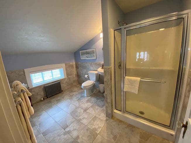The Major General Meade Suite bathroom features a walk in shower, pedestal sink, toilet, and ceramic tile flooring.