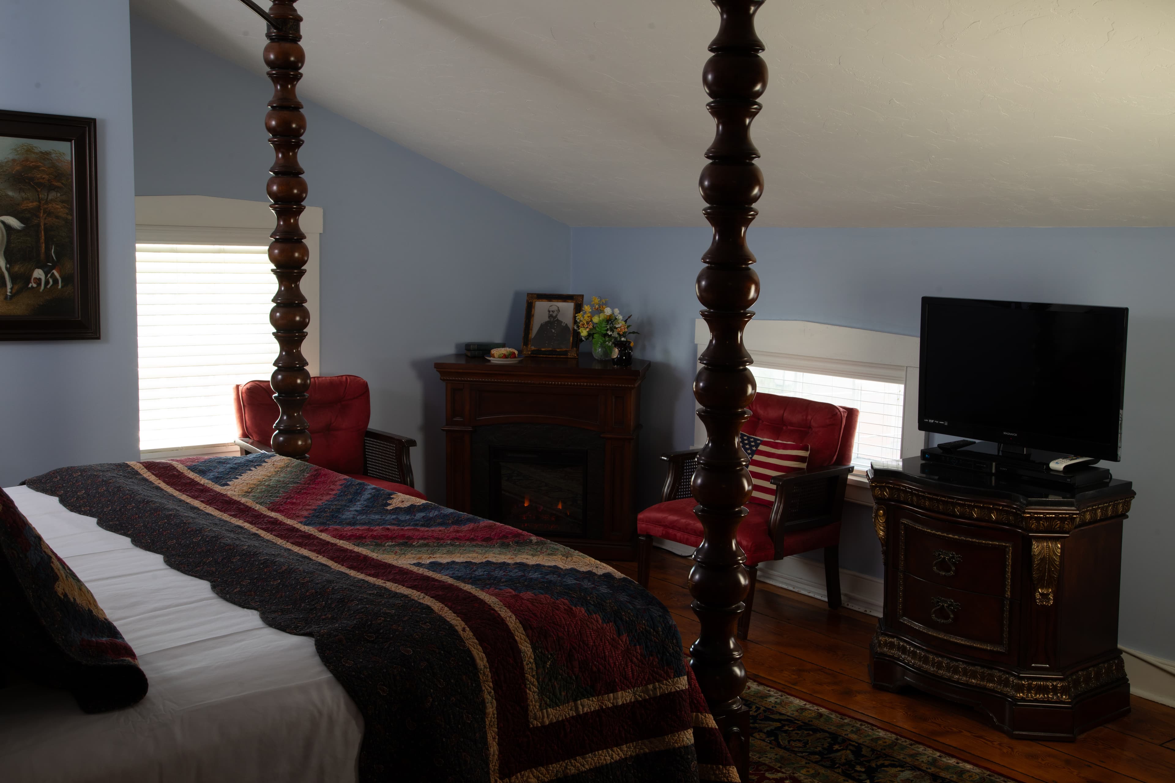 Cozy bedroom featuring a four-poster bed, armchairs, and a television.