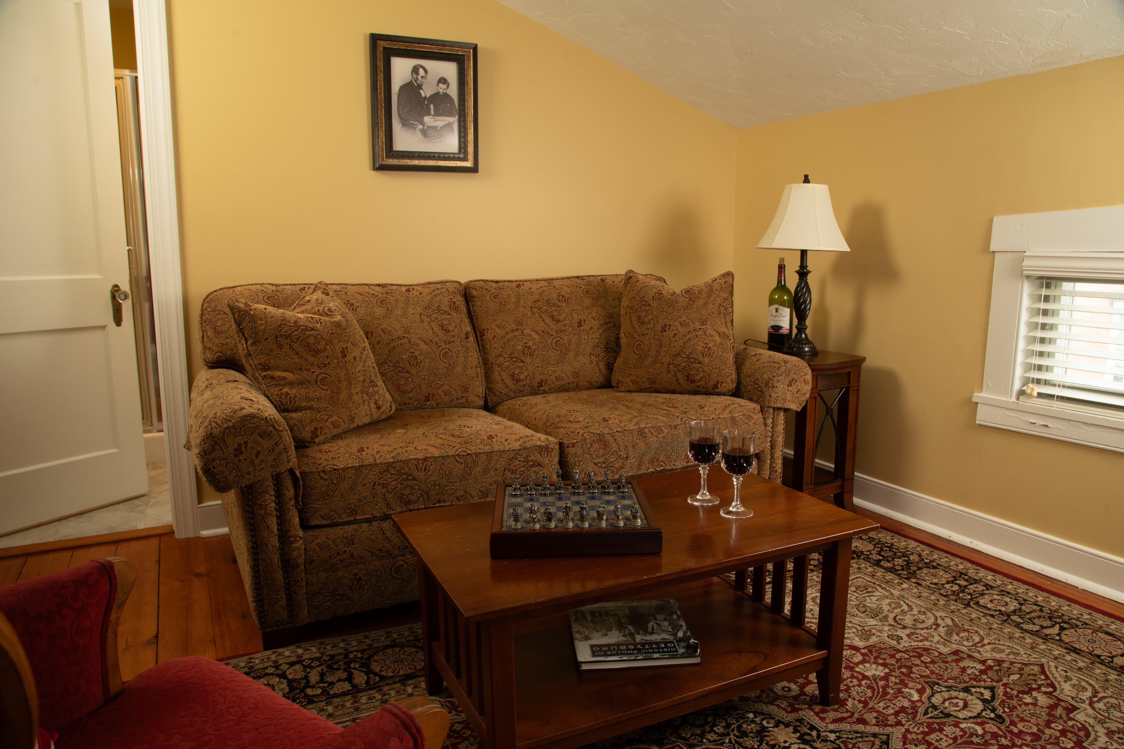 Cozy living room with a brown couch, a wooden coffee table, and two glasses of red wine.