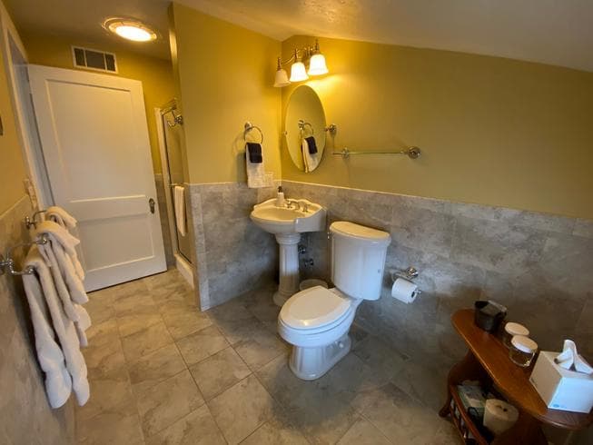 The Lincoln Suite bathroom features a walk-in shower, pedestal sink, toilet, and ceramic tile floors