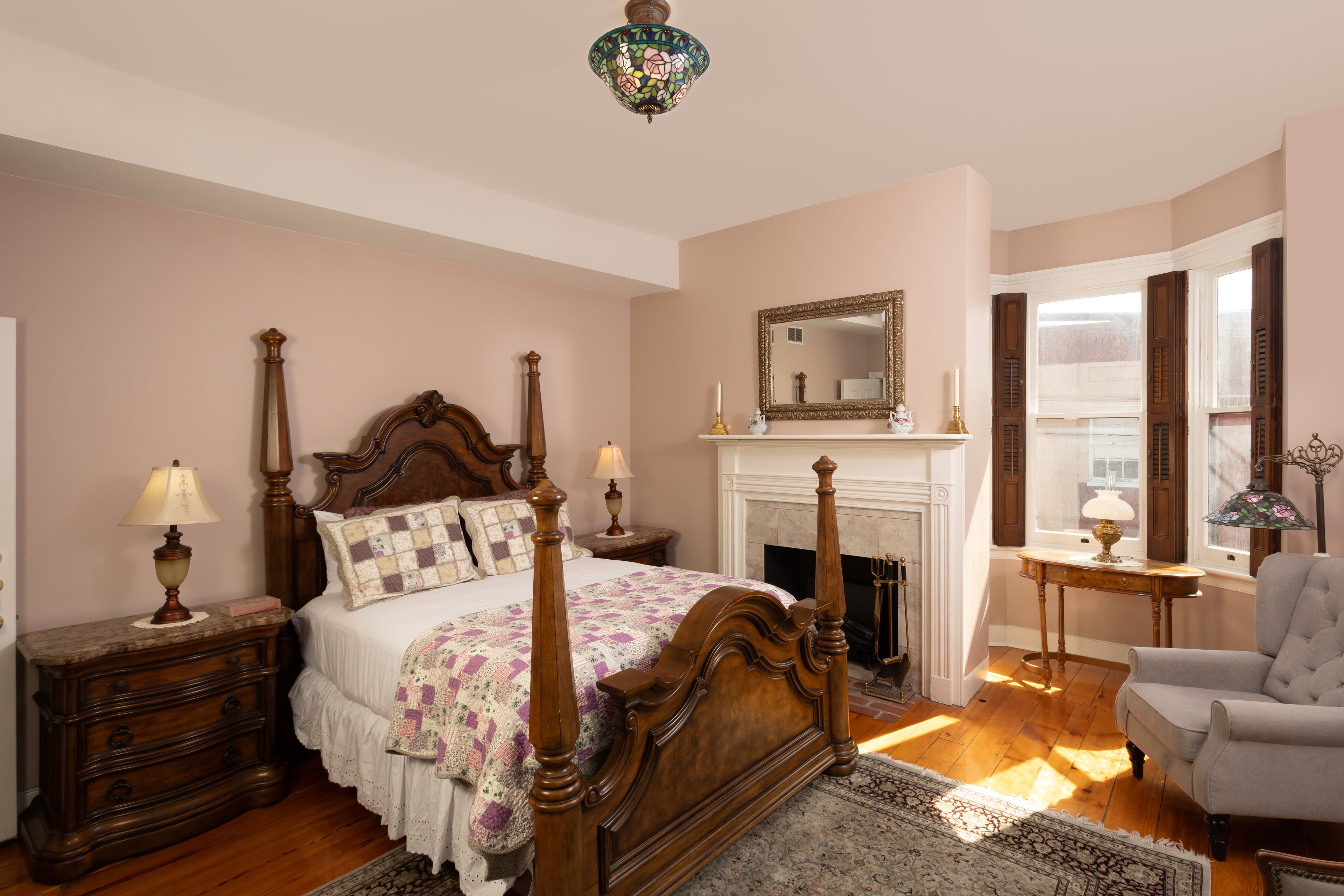 A cozy bedroom featuring a wooden bed, decorative quilt, and vintage furnishings.