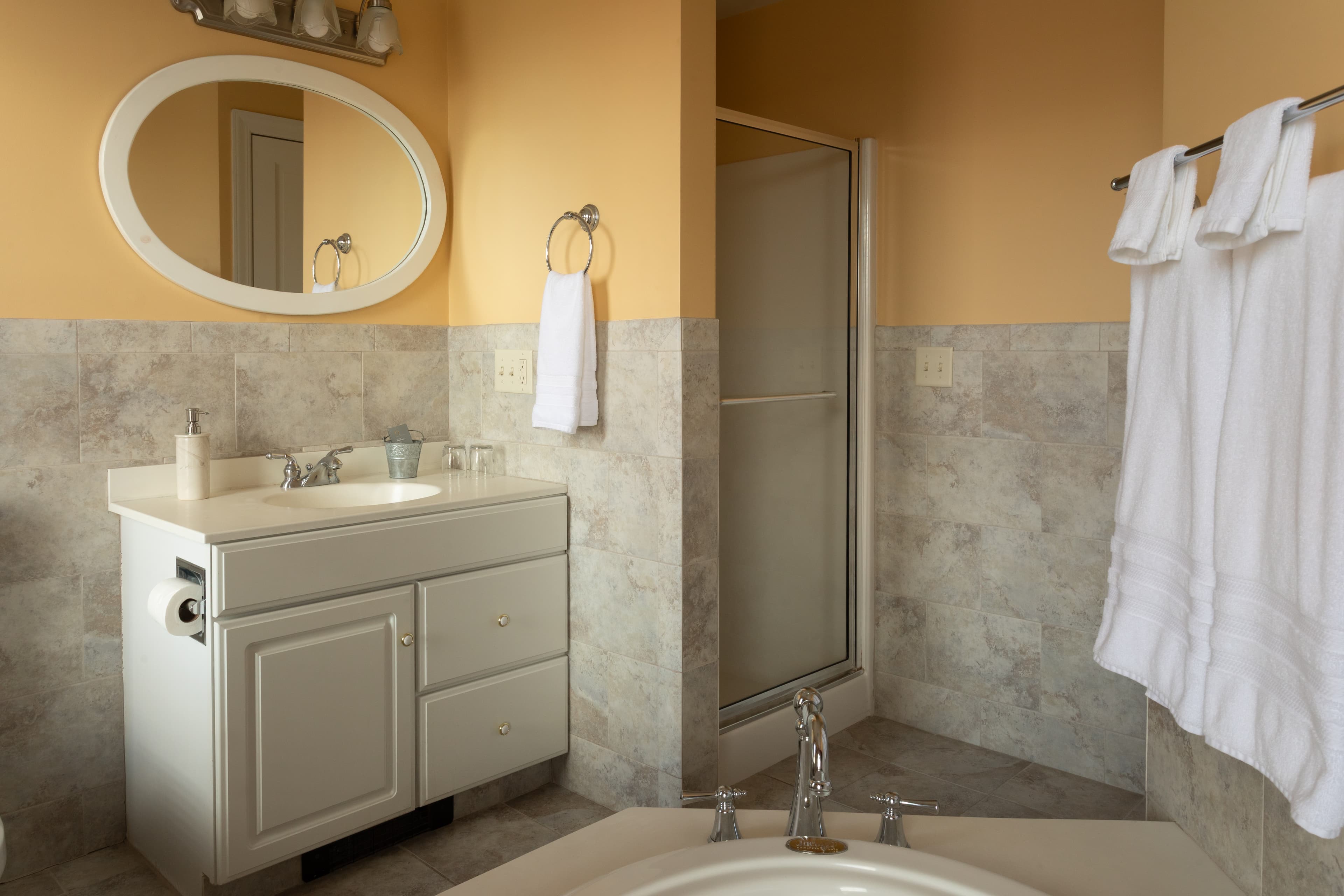Bright bathroom with a white vanity, shower, and fresh towels.