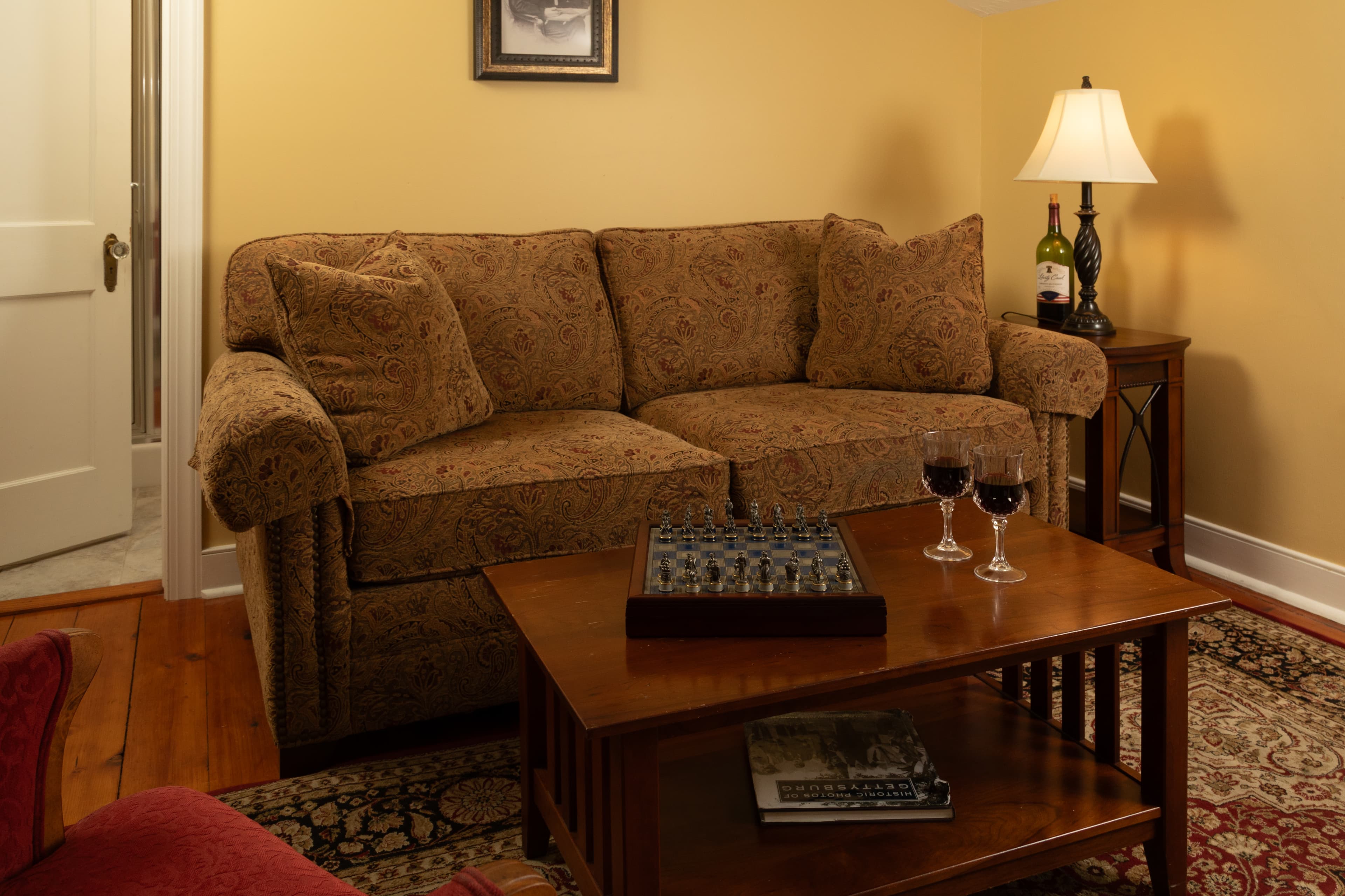 Cozy living room with a brown couch, a wooden coffee table, and two glasses of red wine.