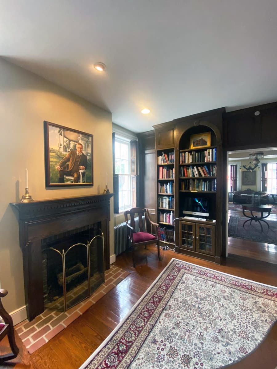 Cozy interior featuring a fireplace, bookshelf, and a portrait on the wall.