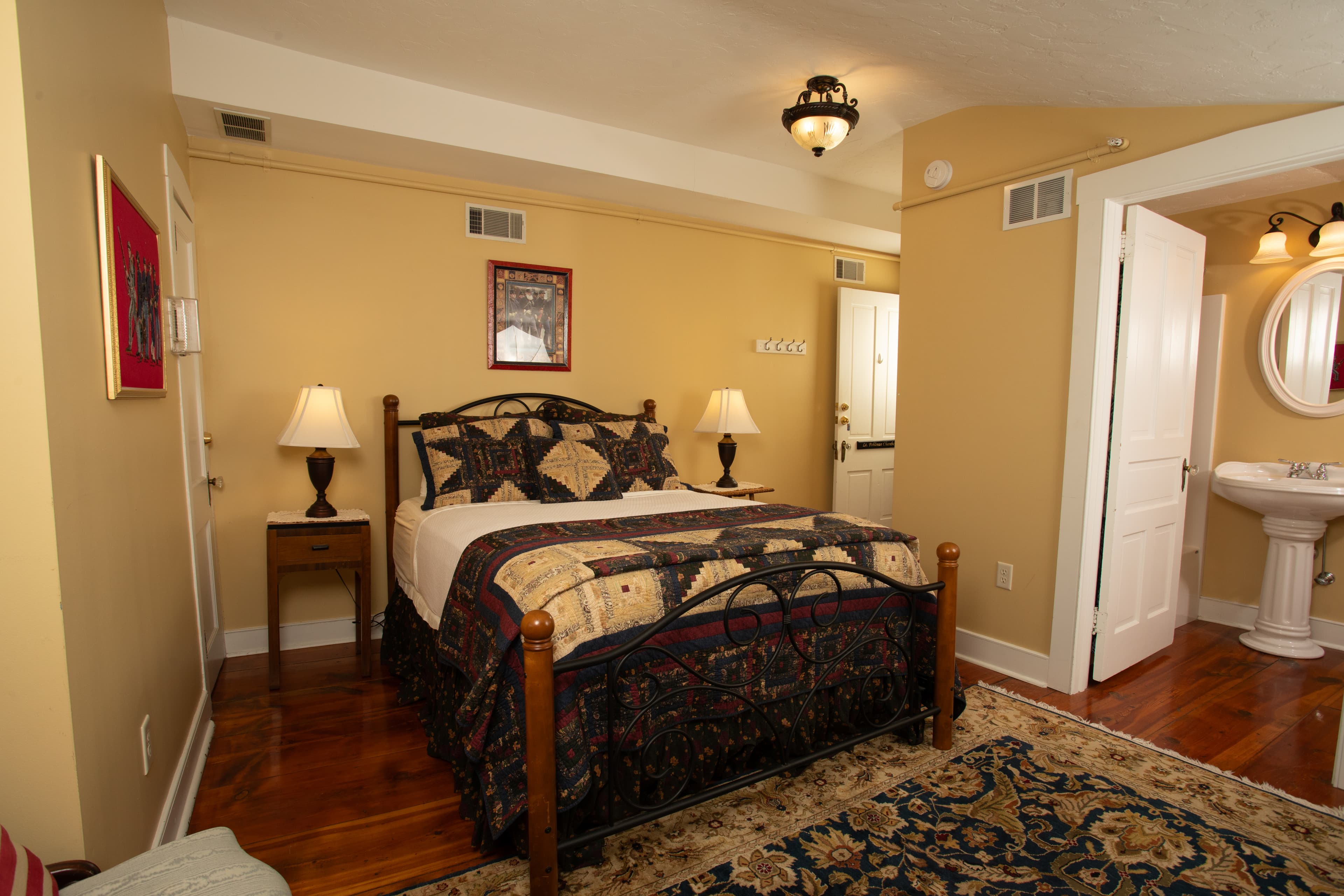 Cozy bedroom with a wrought iron bed, warm yellow walls, and a traditional rug.