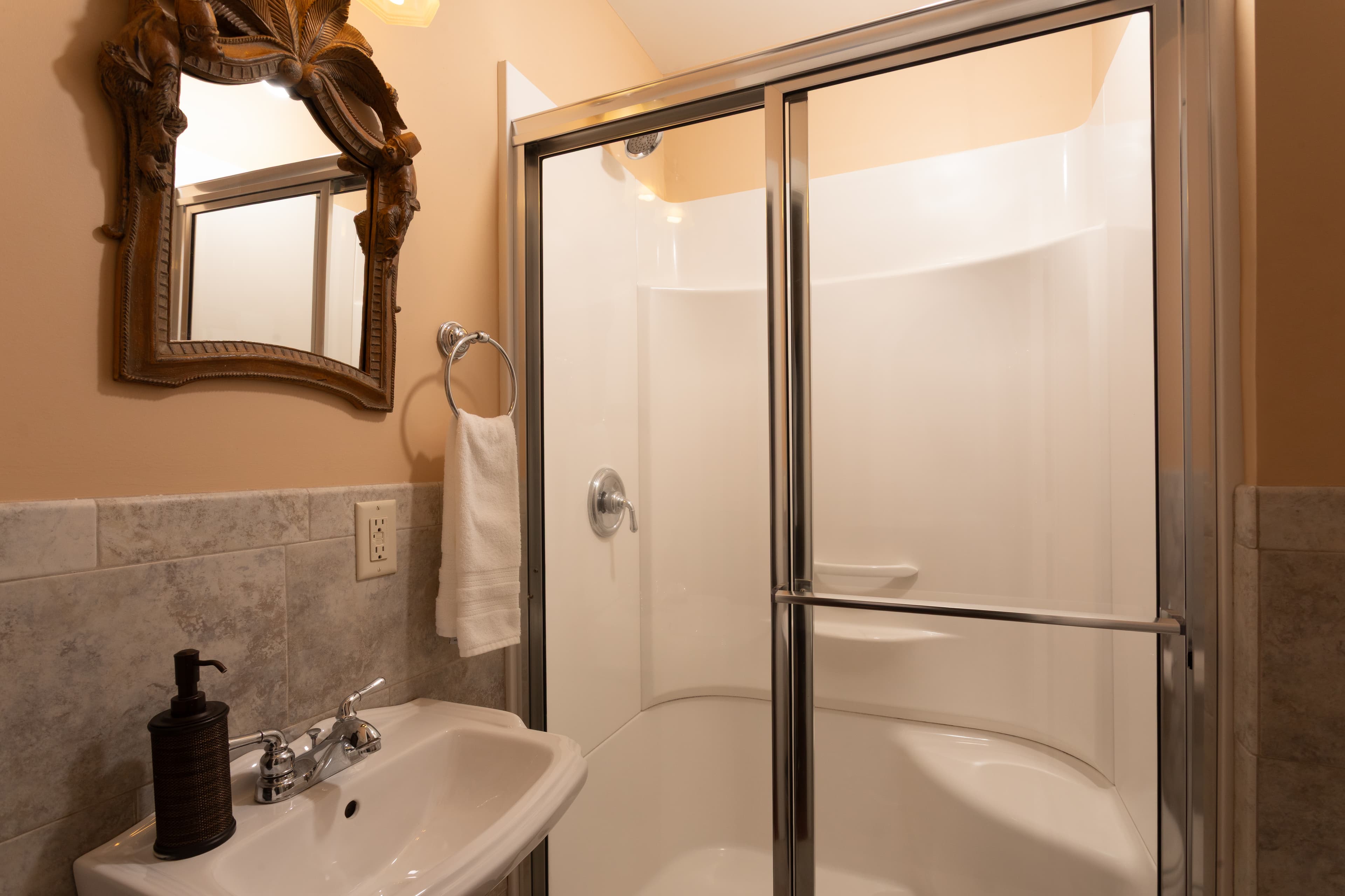 A modern bathroom featuring a shower stall, sink, and decorative mirror.